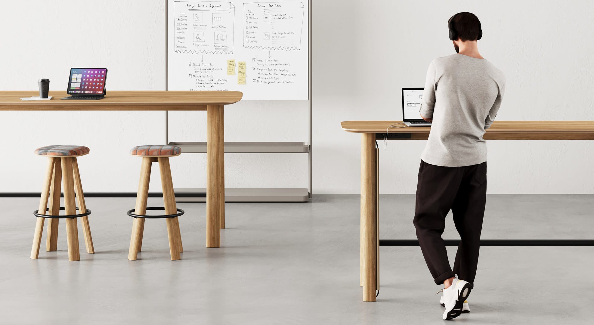 Bazar Table by UFOU. Man at timber standing workstation, with another workstation to the left in the background. 