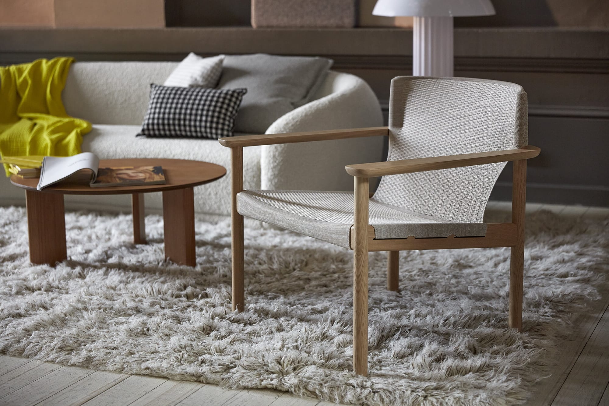 Evo Chair by EFG. Timber and knit Scandinavian inspired armchair on fluffy white rug in living space. 