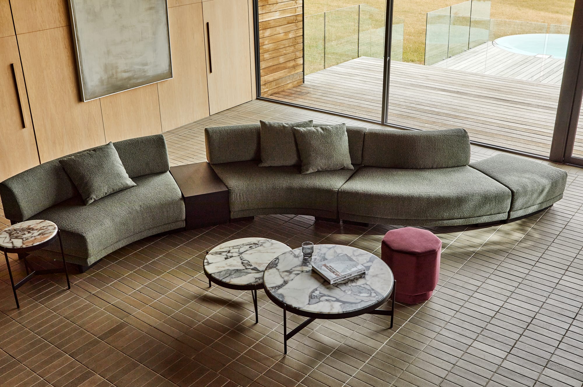 Flex Orbit by GlobeWest from Collection 2025.  Curved moss green couch on tiled floors with marble coffee table.