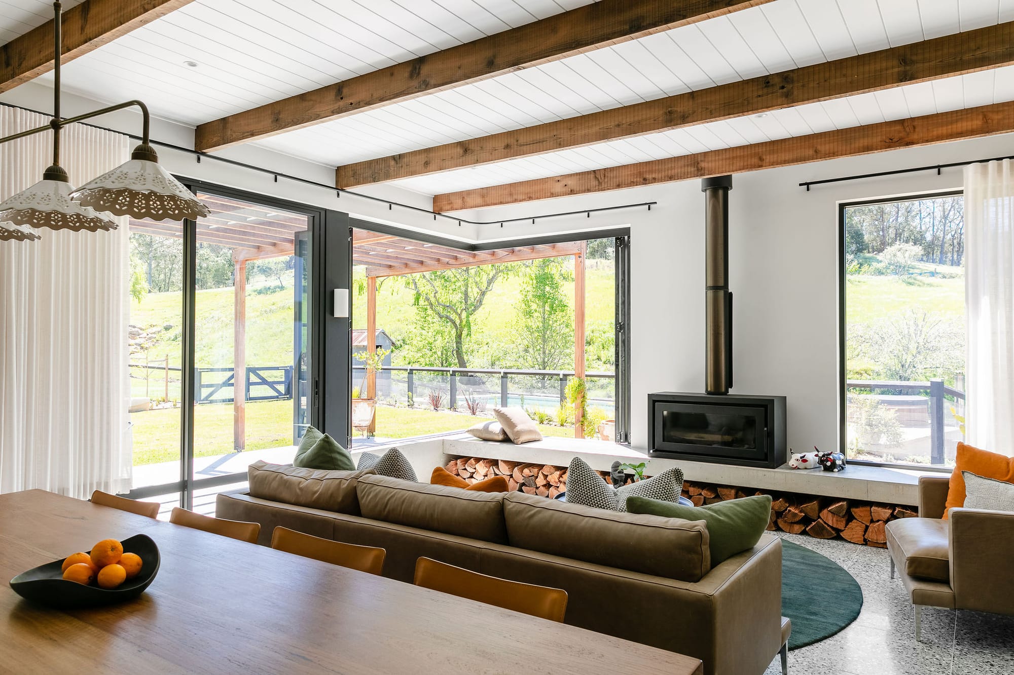 Side of double storey home with brick on ground floor and tin panelling on second floor. Timber beams around front of home. 