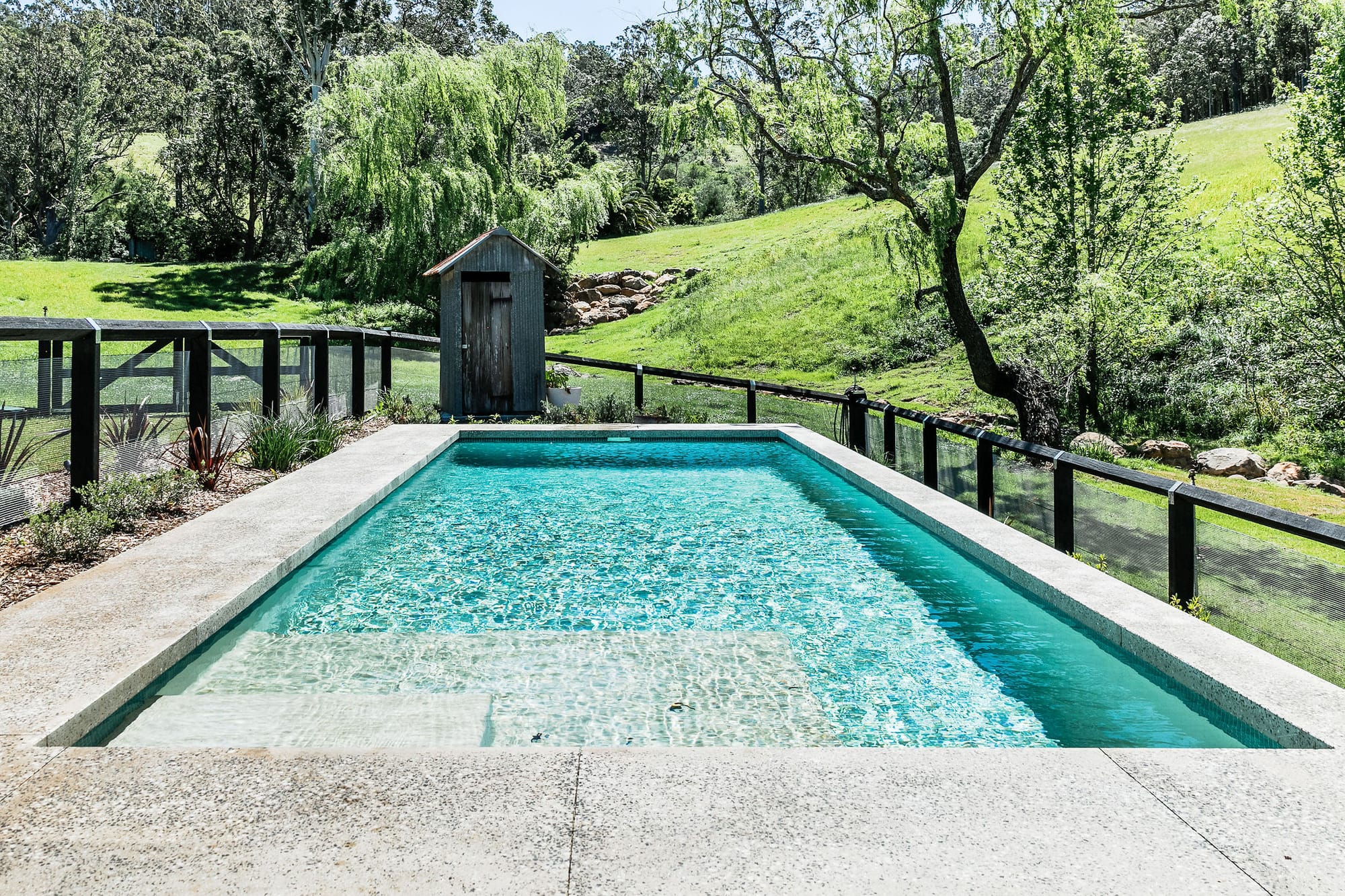 An exterior shot of the pool with the rolling green hills in the background.