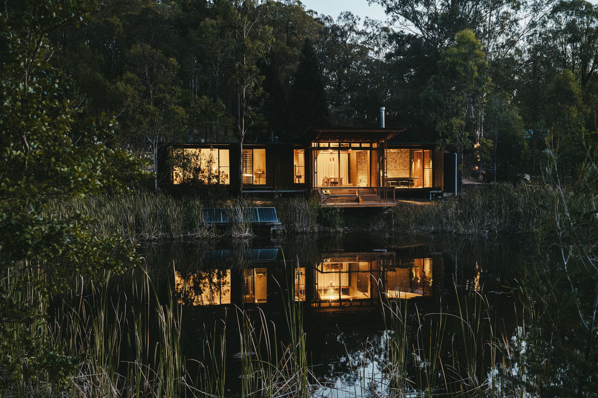 A dusk shot of The Summerhouse showing the house sitting on a dam.