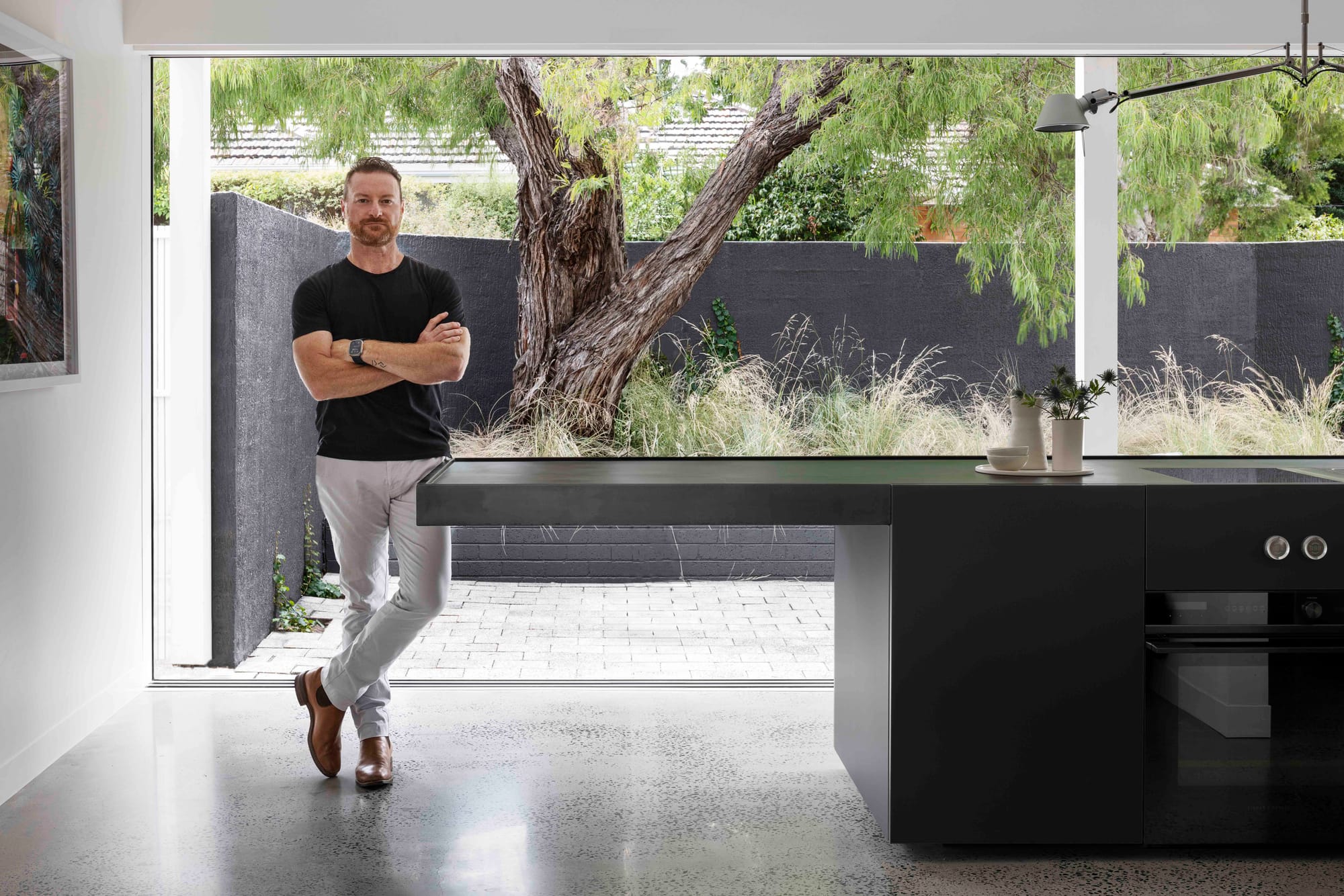 A portrait image of Tony Vella from Rachcoff Vella Architecture standing in his kitchen.