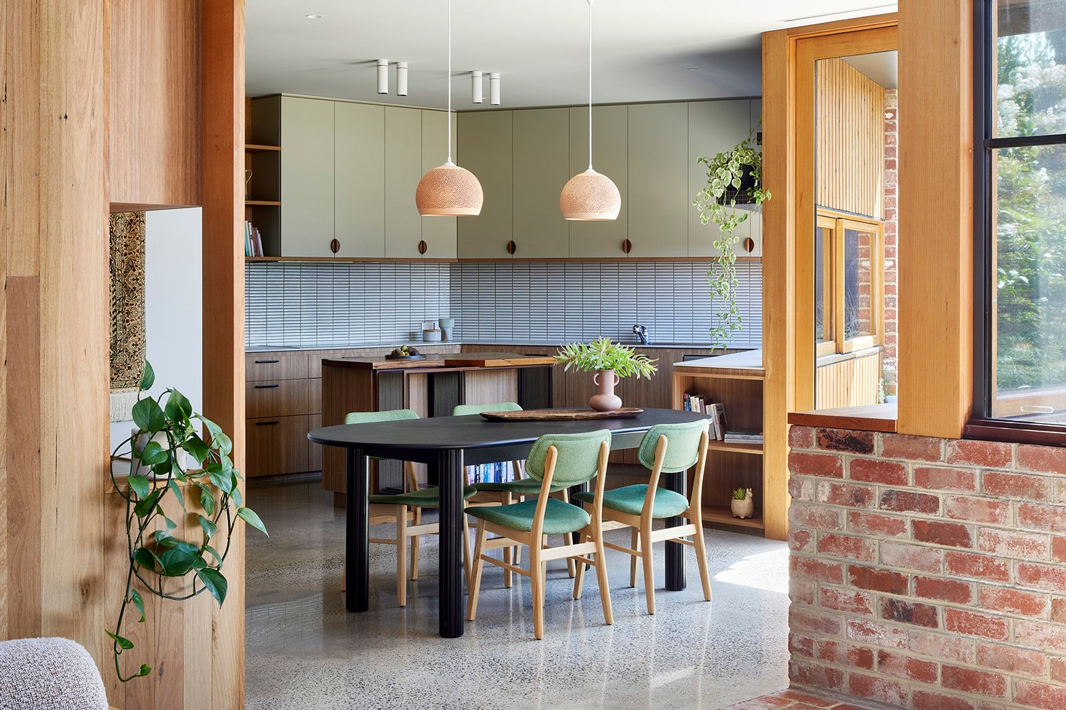 North Balwyn Multi-Gen Housing by Bent Architecture. Kitchen view, brick wall and wooden window and door frame with ceramic tiles and green furniture highlights