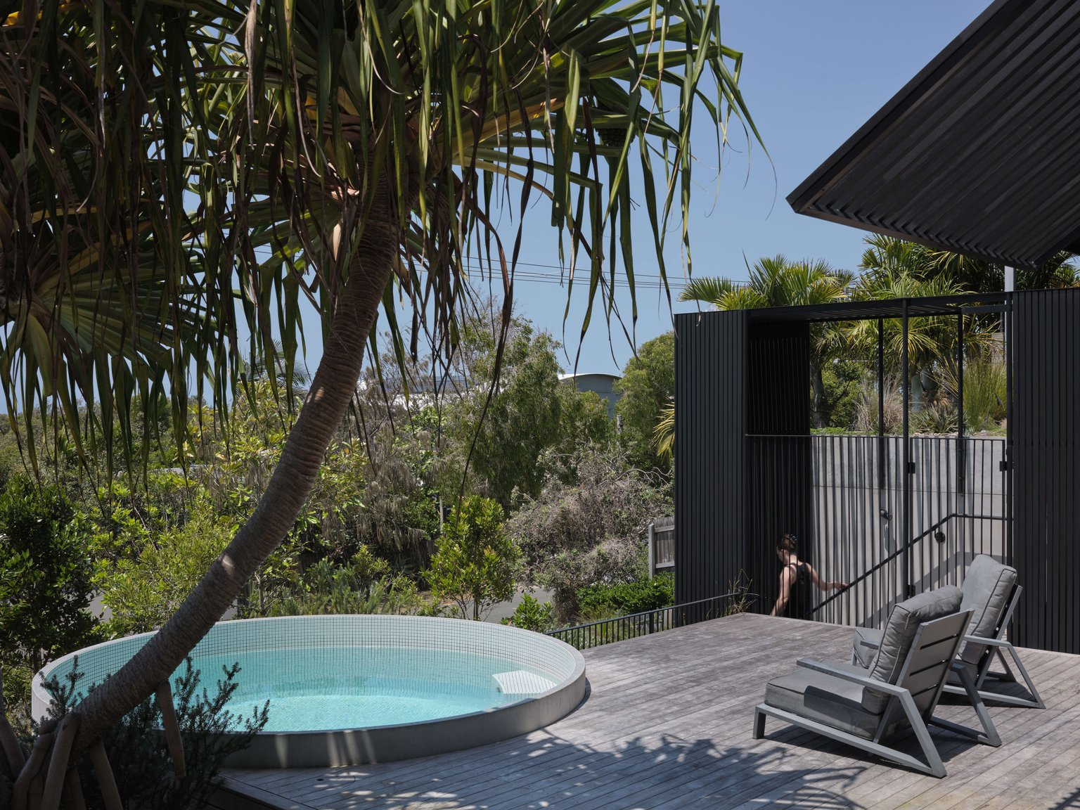 Blok Peregian by Blok Modular. Photography by Chrstopher Frederick ones. Outdoor circled mosaic pool connected to weathered timber deck overlooking dense native bushland. 