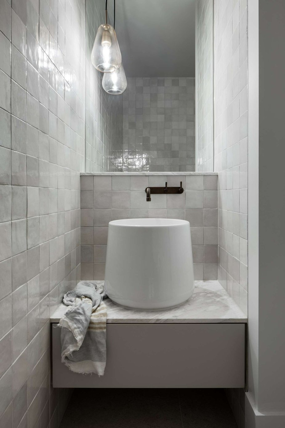 South Terrace Renovation by Chan Architecture. Photography by Tatjana Plitt. Bathroom with shiny wall tiles, tall white basin and glass pendant in front of mirror.