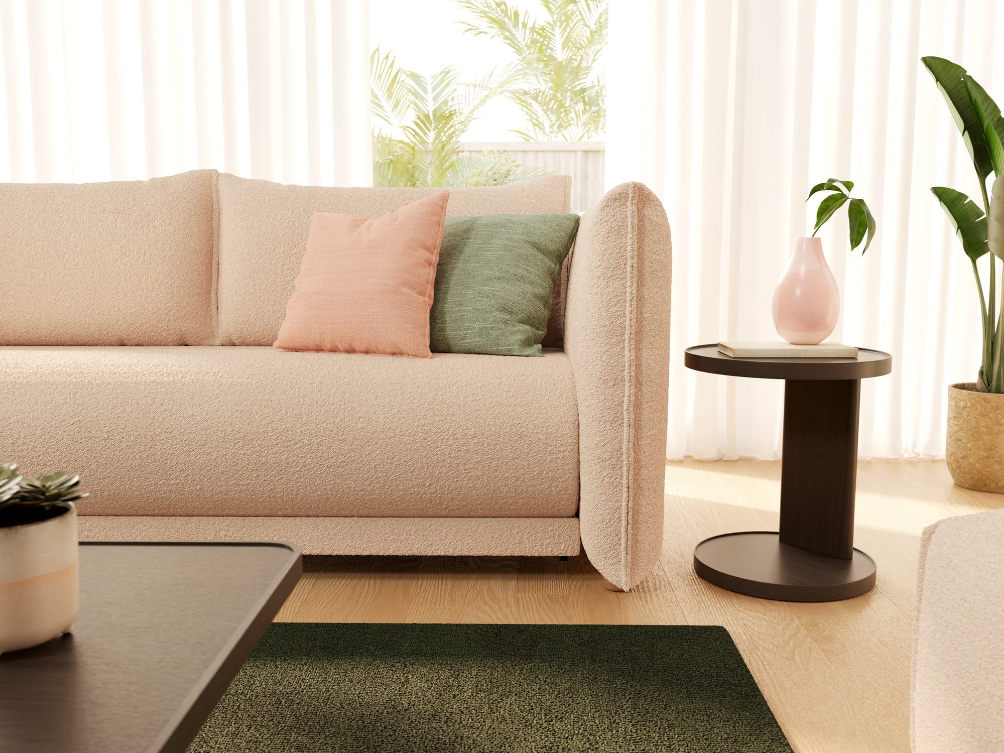 Byron Sofa Bed in Sand Bank by Koala. Close up of a pink boucle couch with pink and green throw cushions, with a dark green floor rug and dark timber bedside table.