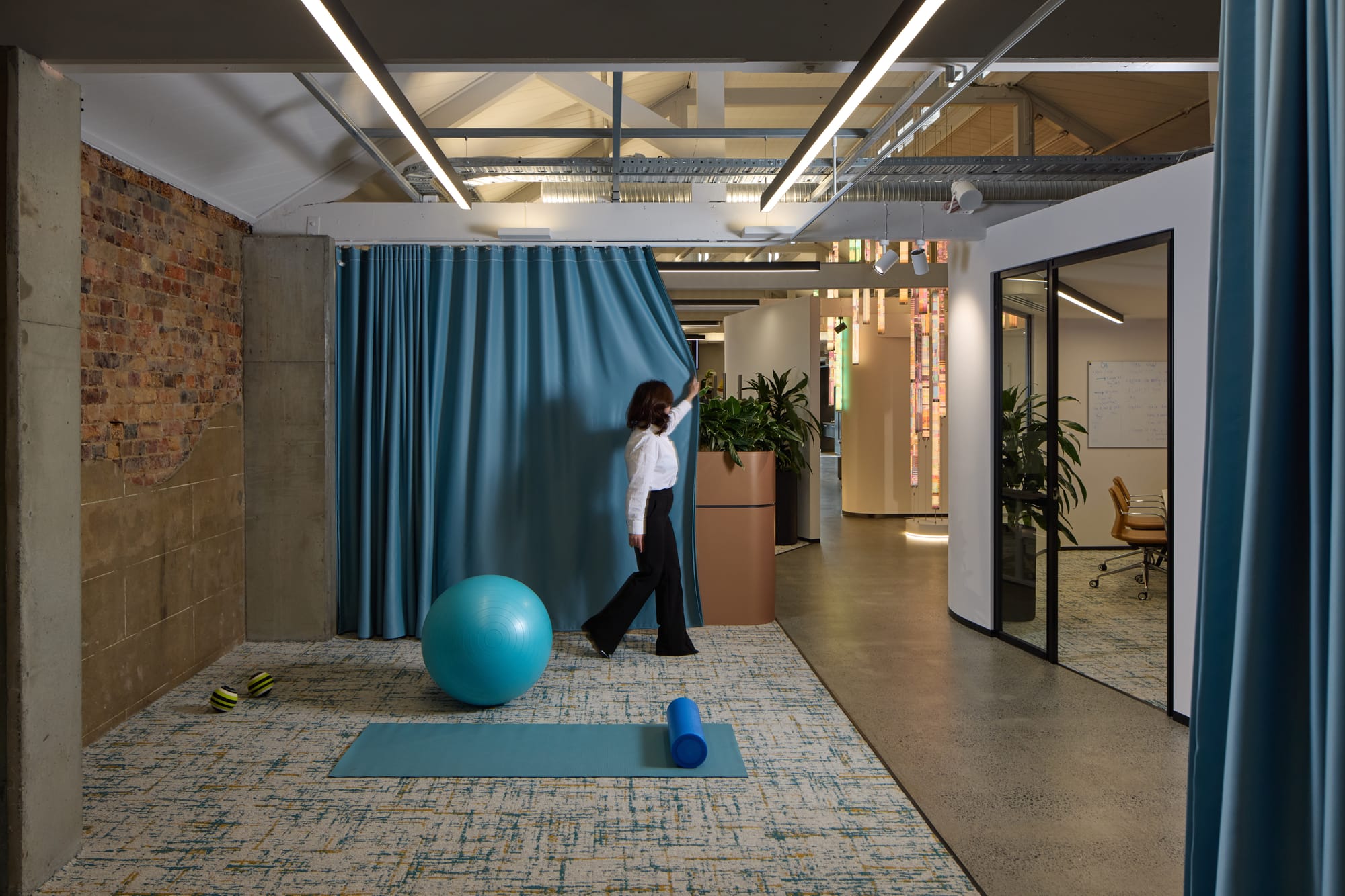 Project Kalkala by M&E Interiors showing a woman pulling a blue curtain in an office fit-out