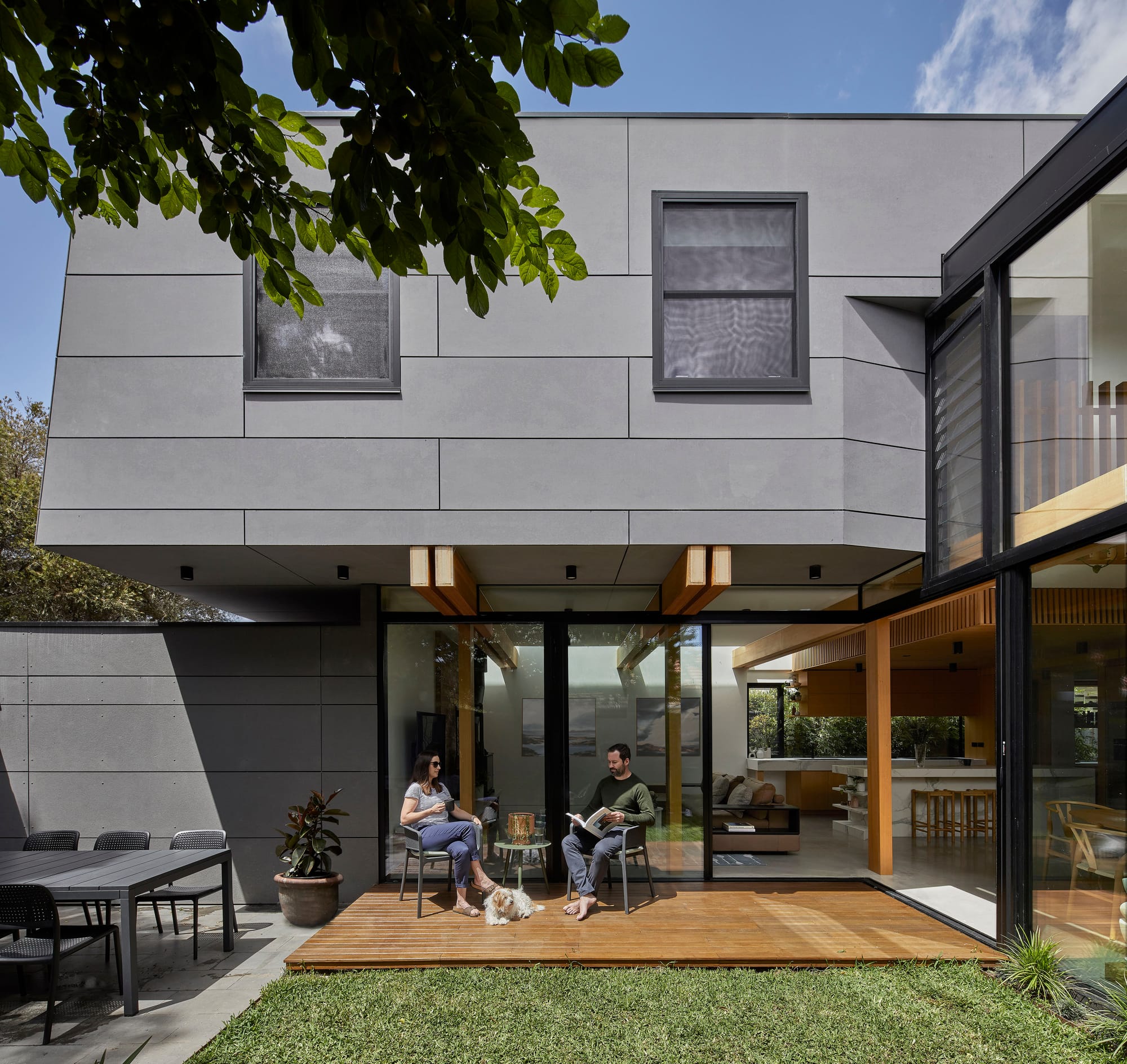 Timber-Lantern House by mcmahon and nerlich. Photography by Dave Kulesza. Rear afacde and garden of double storey home with timber deck, concrete patio with dining set and full height sliding glass doors connecting indoors and out.