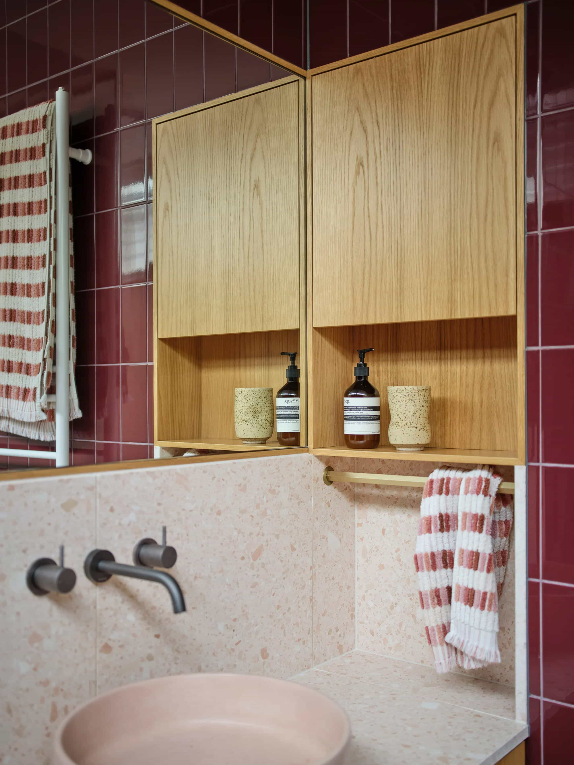 Zig Zag House by True Story. Photography by Dean Bradley. Bathroom with burgundry red wall tiles, pink speckled counter and splashback, pink sink and integrated timber wall storage.