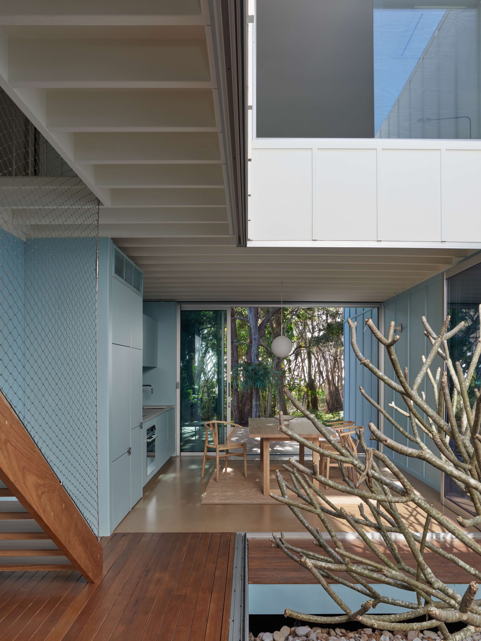 Blok Peregian by Blok Three Sisters. Photography by Christopher Frederick Jones. Home with timber floors, light blue walls, a timber dining table and large open-air courtyard.