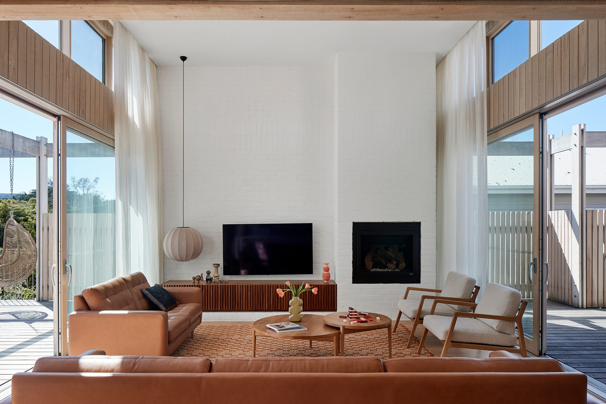 The Blairgowrie Beach Club by Bower Architecture & Interiors. Photography by Shannon McGrath. Living room space with tv against the wall surrounded by brown colored furnitures.