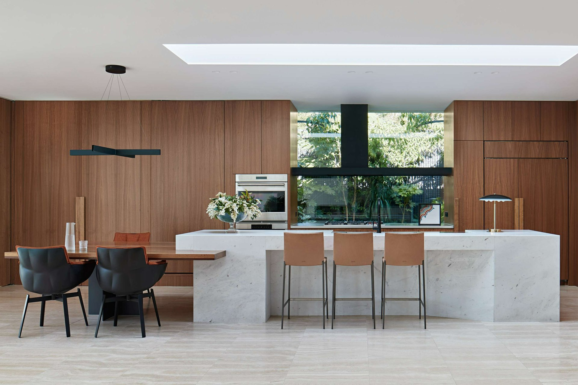 New Modern by Bower Architecture & Interiors. Photography by Shannon McGrath. Kitchen with marble benchtop flowing into timber table, with timber cabinetry.