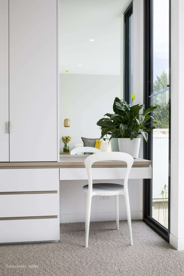 Mason Street Residence by FYC Architects. Photography by Rachael Dere. Integrated white deck and cabinetry in bedroom with mirror backsplash and white chair.