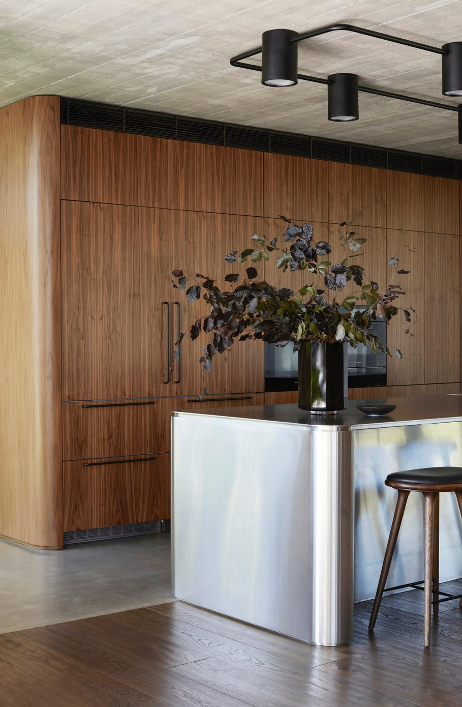 Casa Figueira by buck&simple. Photography by Prue Ruscoe. Kitchen with timber cabinetry with curved finished, and a chrome island benchtop.