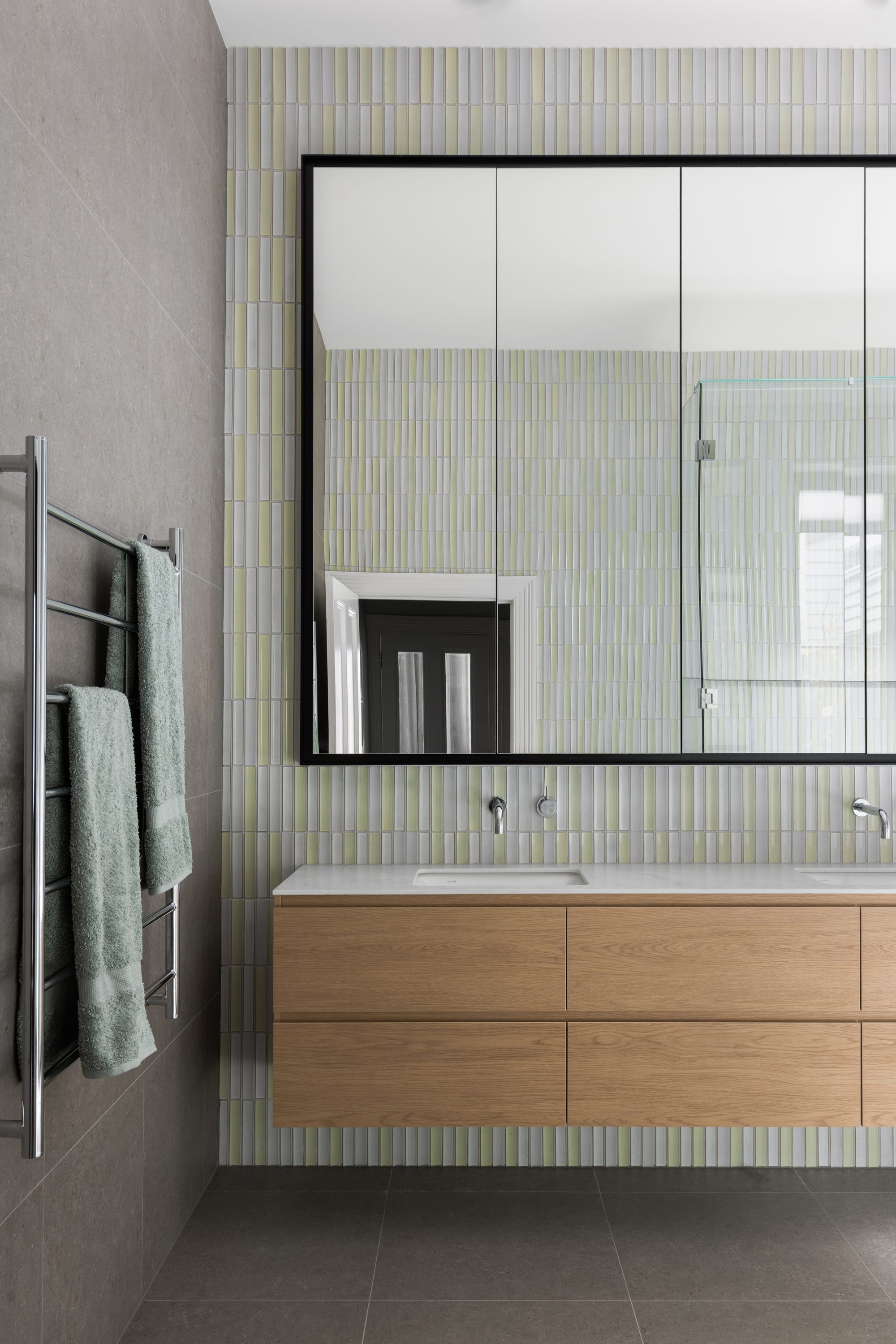 Auburn Residence by Chan Architecture. Photography by Elise Scott. Bathroom with grey floor and wile walls, floating timber cabinet and mosaic green splashback wall.