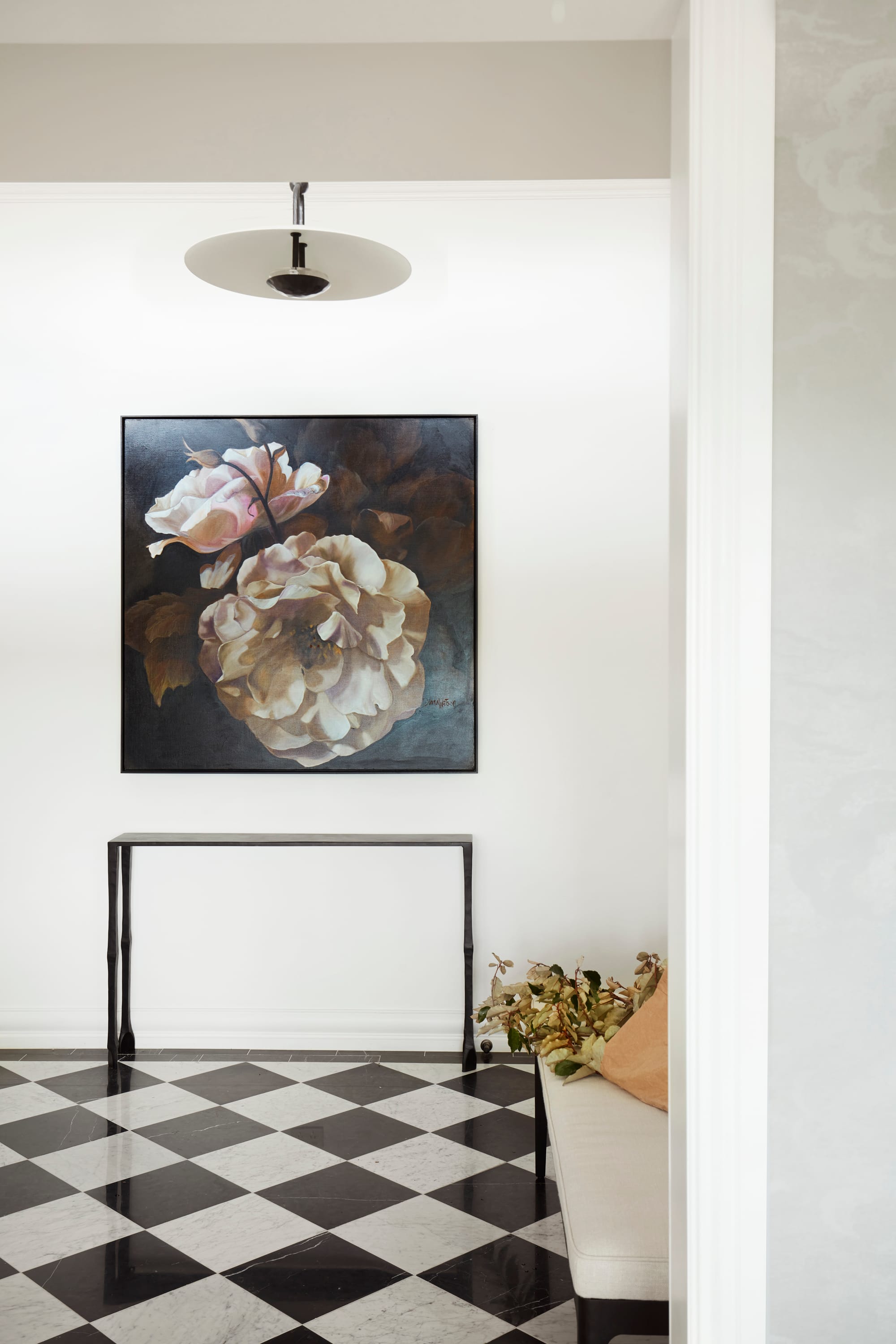 Marathon Road by Marylou Sobel Interior Design. Photography by Prue Ruscoe. Entry with black and white tile checkered flooring, white walls, black metal sideboard and large floral artwork.