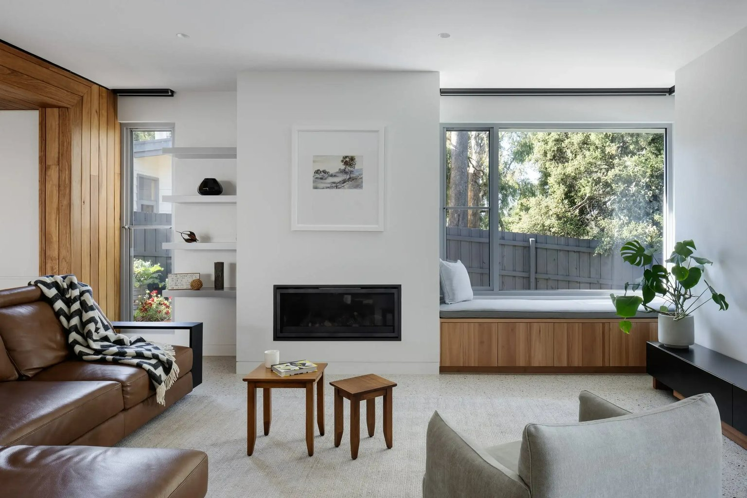Earth + Sky House by Kirsten Johnstone Architecture. Photography by Tatjana Plitt. Interior living space with white walls, fireplace, timber window seats and brown leather couch. 