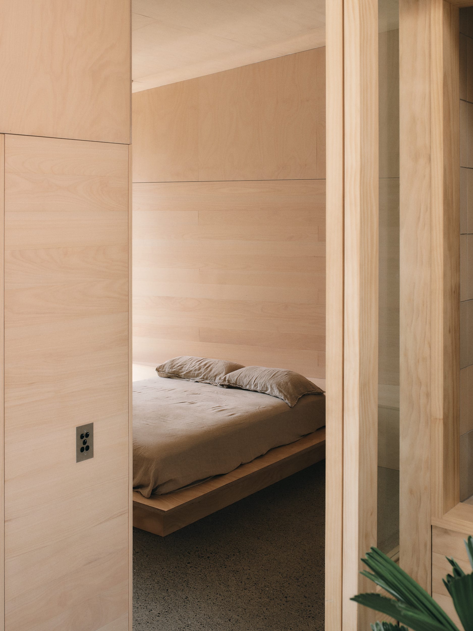 Mapleton House by Atelier Chen Hung. Photography by David Chatfield. Simple bedroom with concrete floors, timber walls, doors and bed frame.