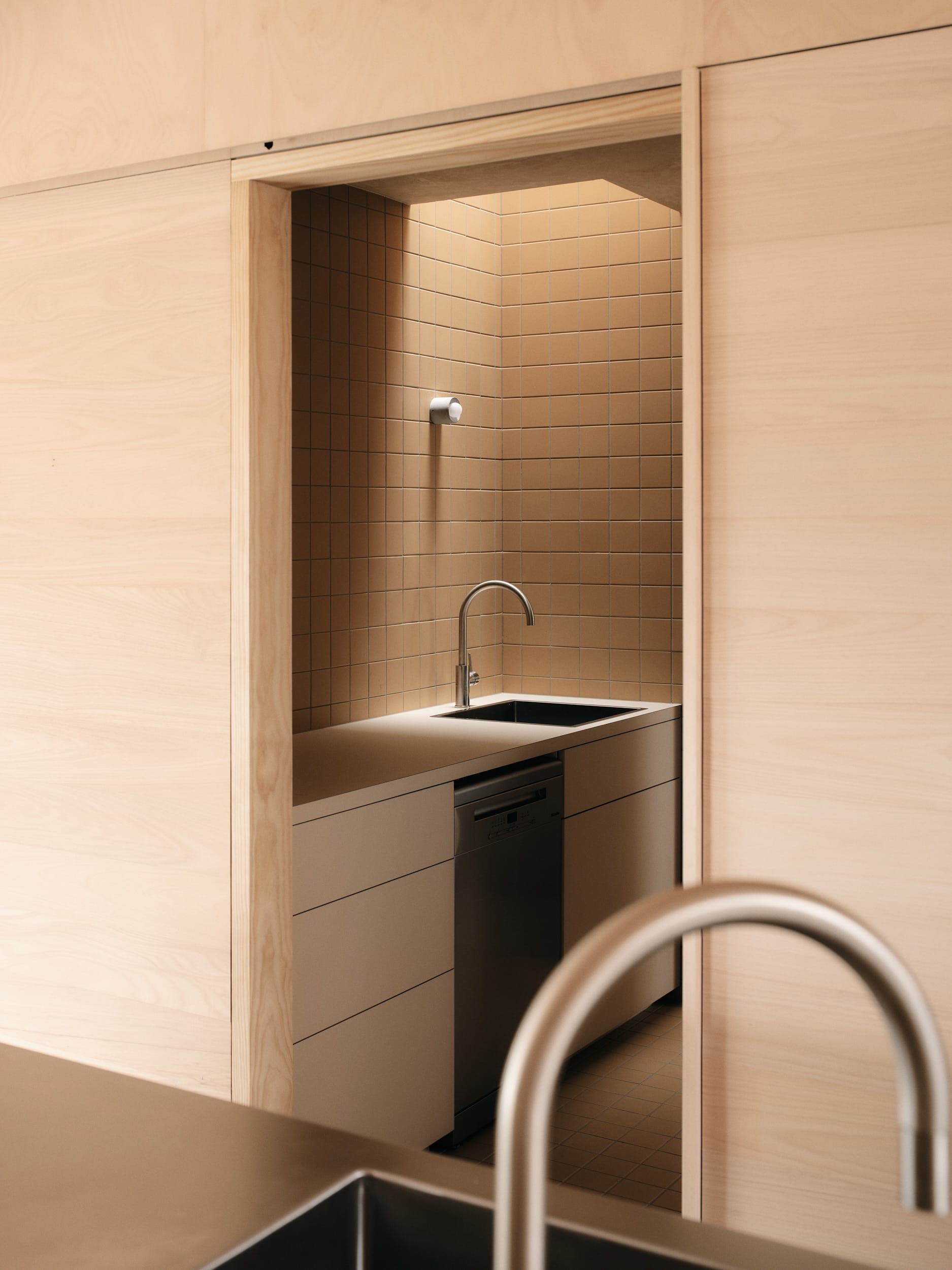 Mapleton House by Atelier Chen Hung. Photography by David Chatfield. Scullery with white cabinetry, silver appliances and tapware and beige wall tiles.