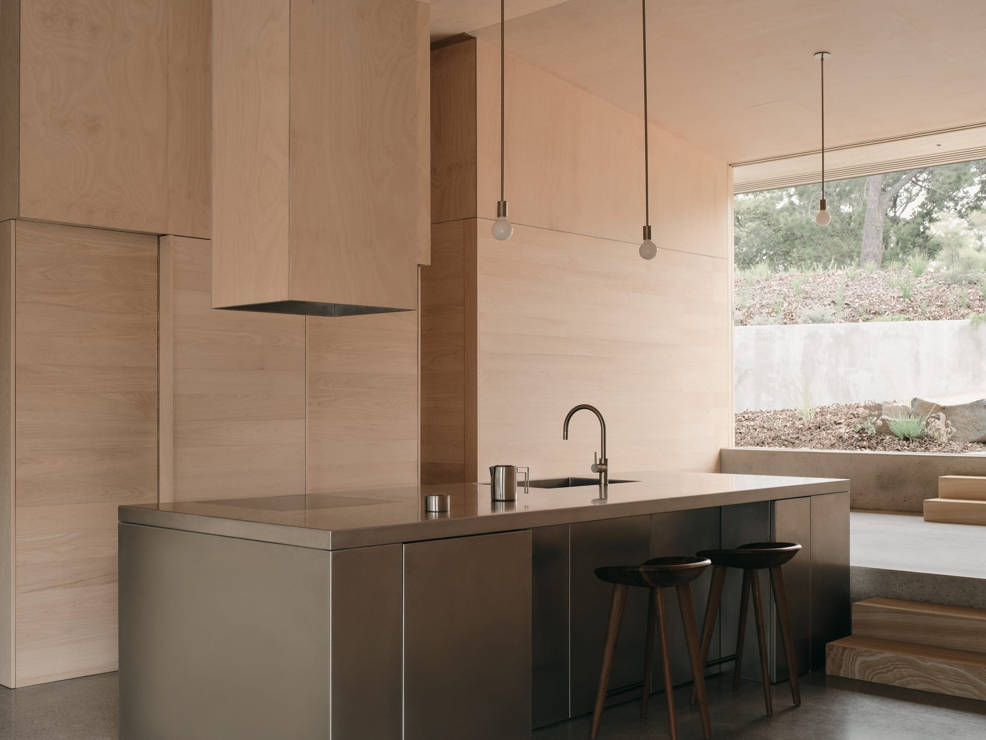 Mapleton House by Atelier Chen Hung. Photography by David Chatfield. Sleek stainless steel kitchen in room with timber walls, stairs and ceiling and concrete floors.