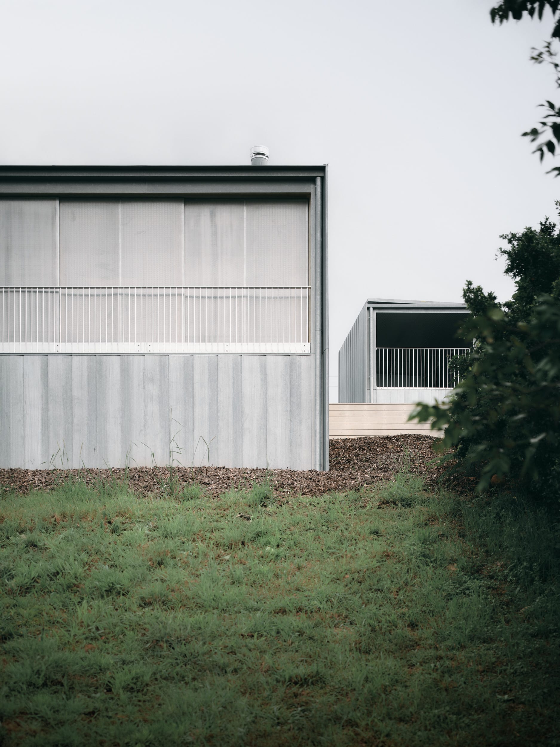 Mapleton House by Atelier Chen Hung. Photography by David Chatfield. Zinc-clad home with white balustrade around balcony and large shade awnings blocking view inside.