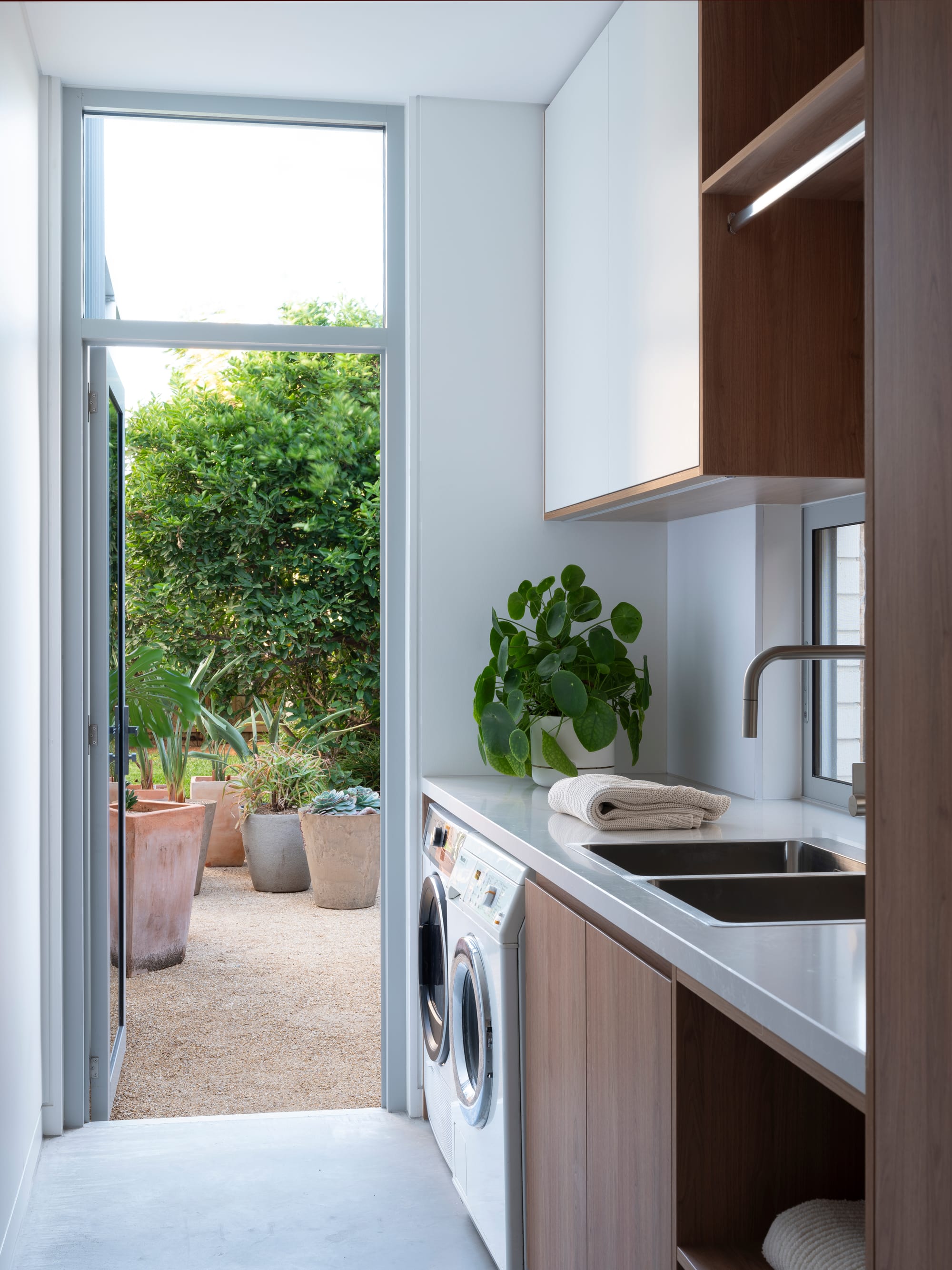Merrilands by BIJL Architecture. Photography by Tom Ferguson. Laundry with timber joinery, white countertop and door out to gravel courtyard.