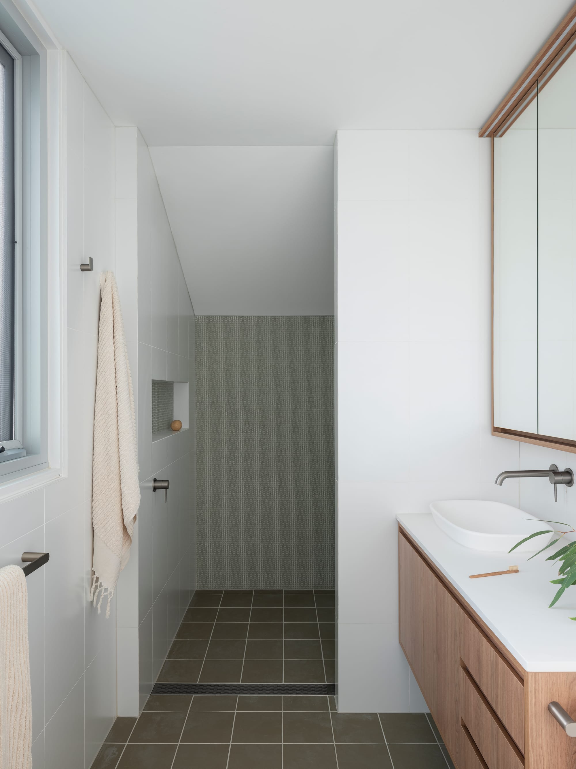 Merrilands by BIJL Architecture. Photography by Tom Ferguson. Bathroom with olive floor tiles, green tiles in shower and wooden cabinetry.