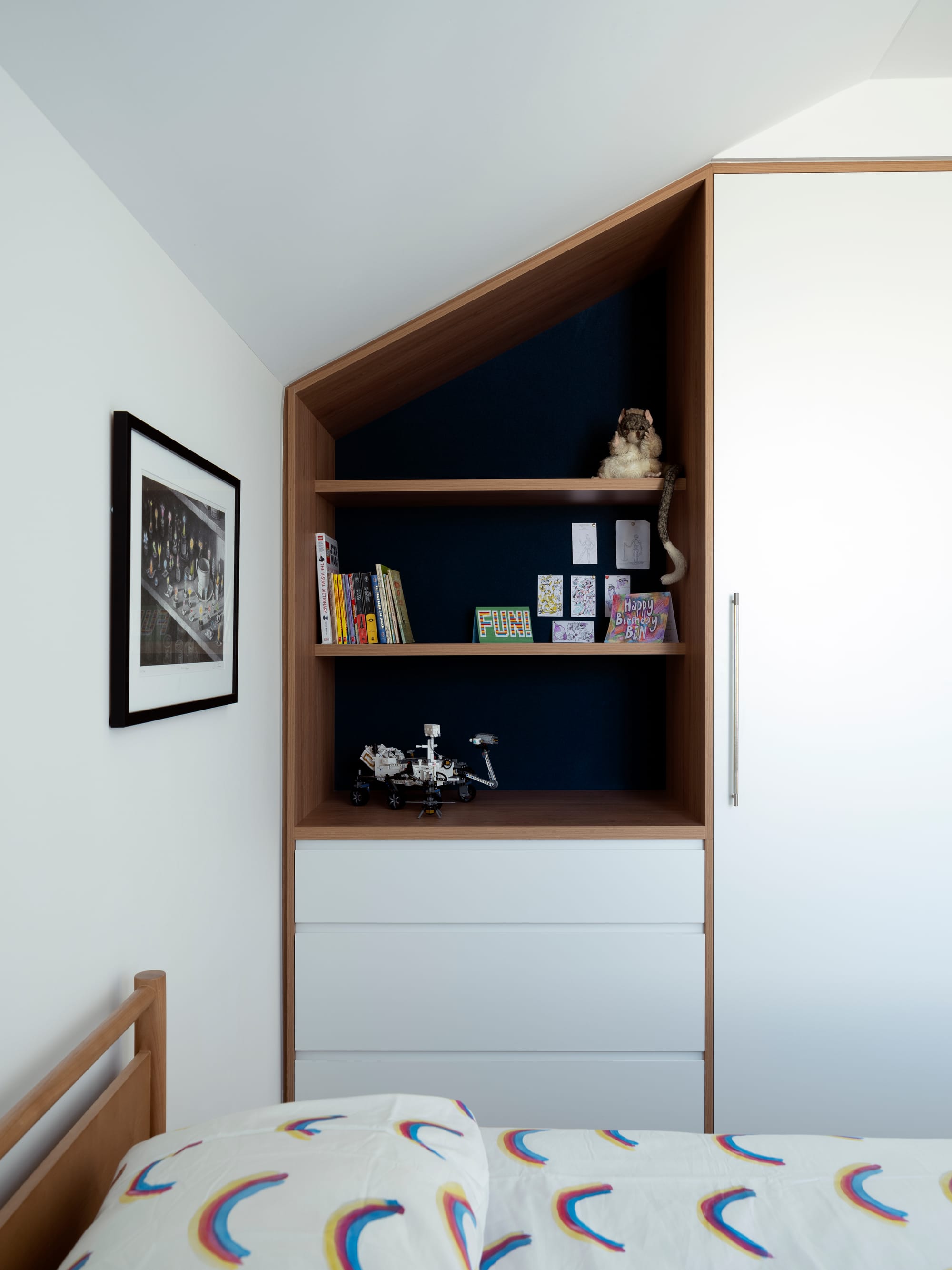 Merrilands by BIJL Architecture. Photography by Tom Ferguson. Bedroom with integrated white and timber storage and timber bedframe with rainbow print bedding.