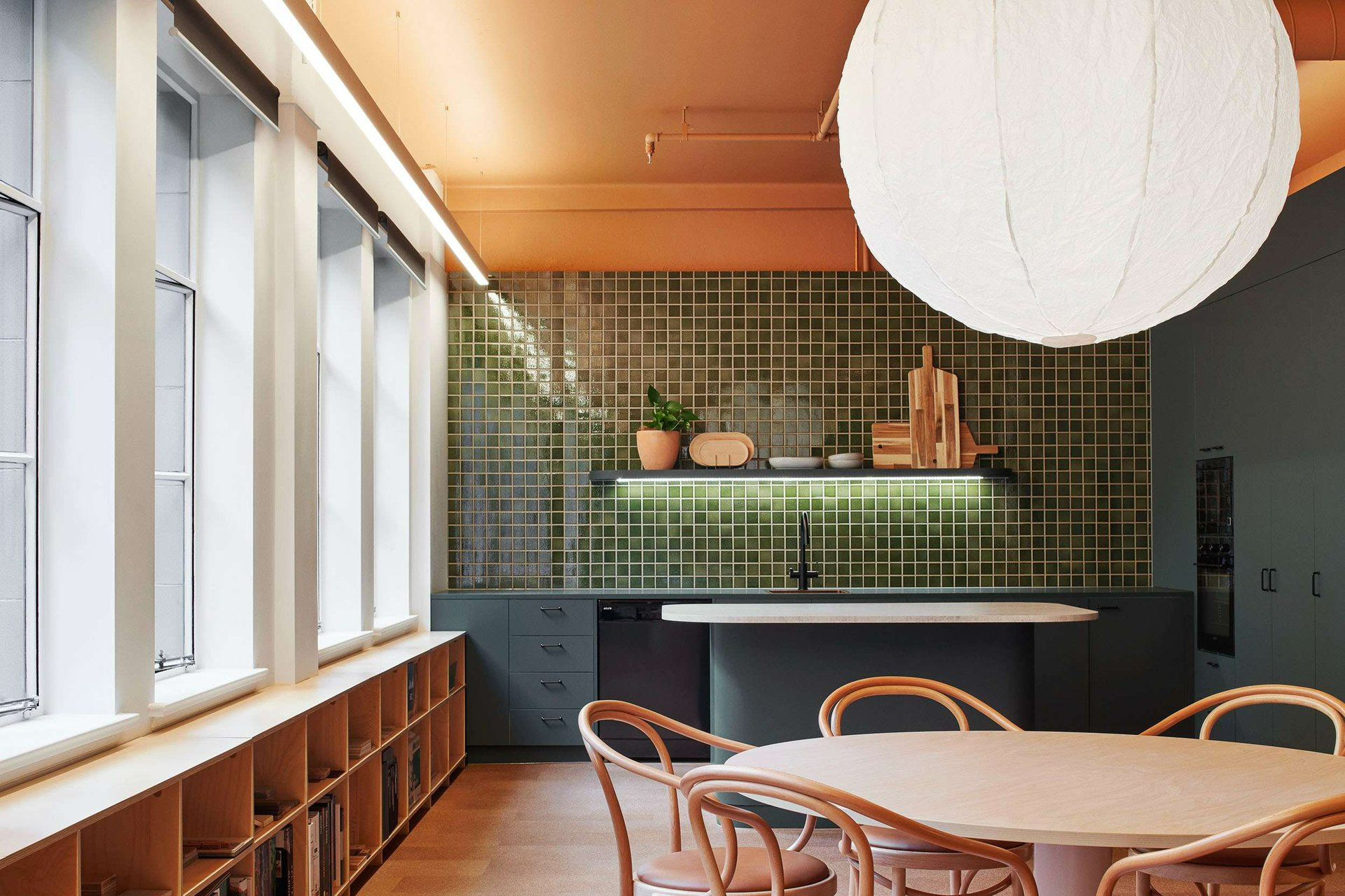 Hames Sharley Melbourne Studio by Hames Sharley. Photography by Nicole England. Kitchnette space with dark green cabinetry, dark green mosaic splashback tiles and timber furnishings.