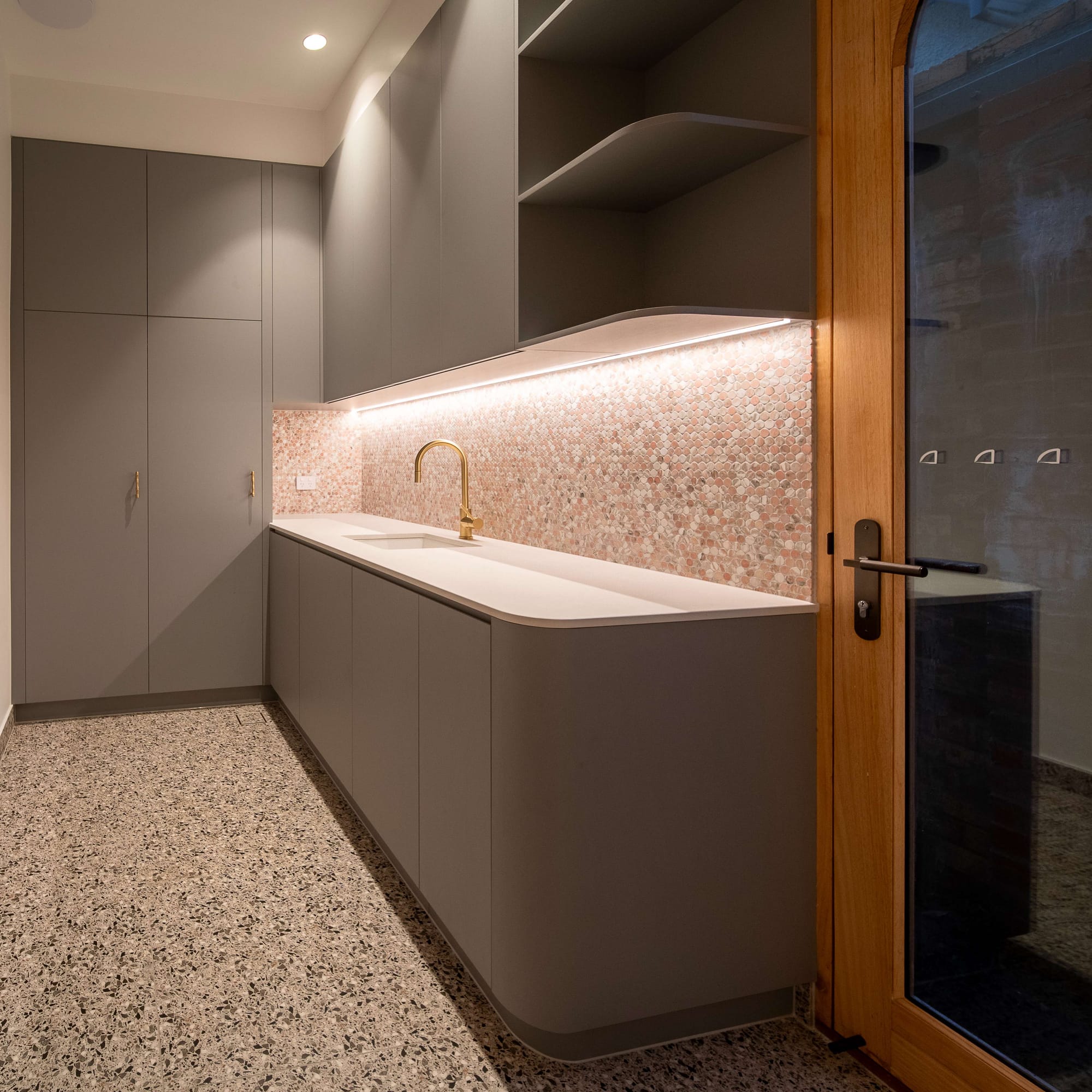 Murrumbeena by PREM.BUILT. Image copyright of Prem.Built. Laundry with sage green cabinetry, mosaic splashback and terrazzo flooring. 