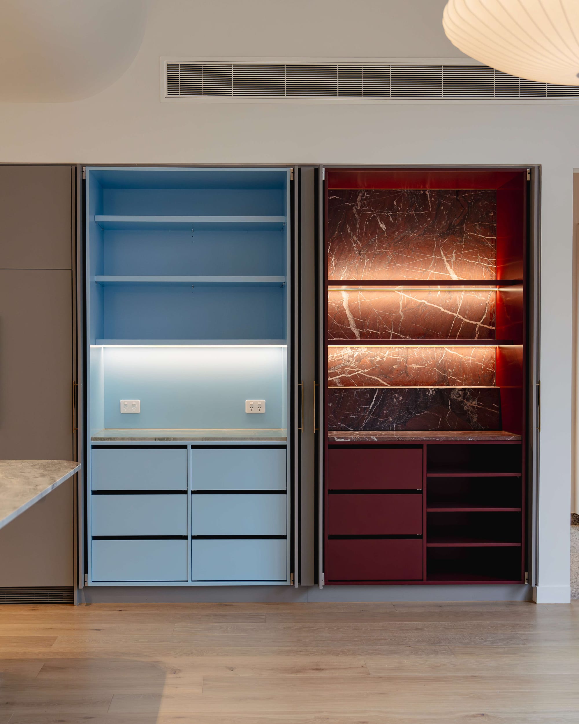 Murrumbeena by PREM.BUILT. Image copyright of Prem.Built. Side-by-side storage in kitchen space with light blue interior storage and burgundy with inlaid stone splashback. 