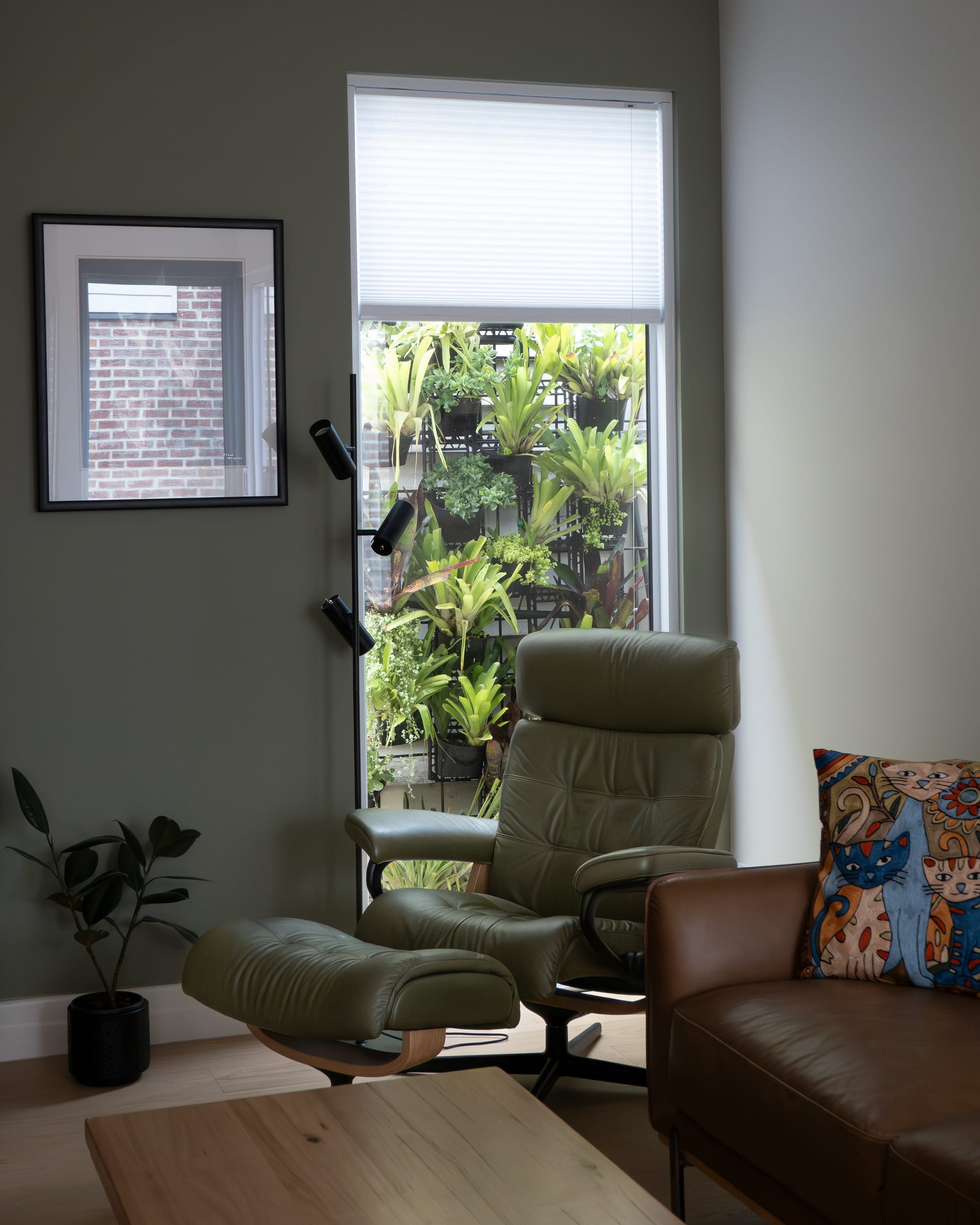 Port Melbourne 2.0 by PREM.BUILT. Image copyright of Prem.Built. Living room with sage walls and sage leather recliner chair with matching footstool, alongside brown leather couch and timber coffee table. 