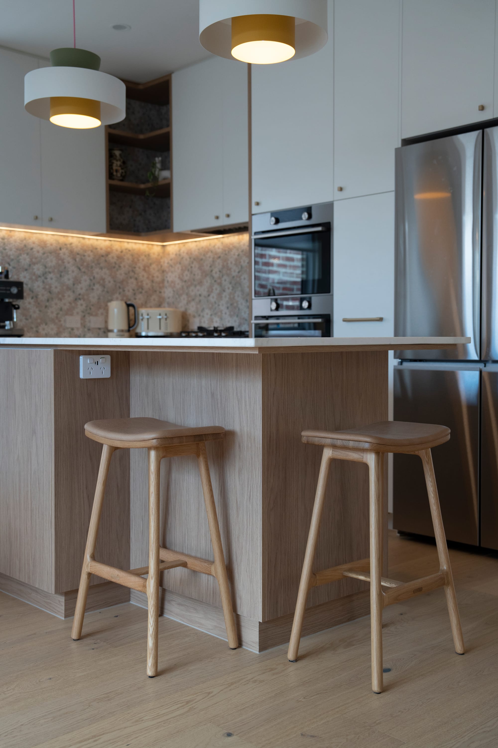 Port Melbourne 2.0 by PREM.BUILT. Image copyright of Prem.Built. Kitchen with timber island bench with timber stools, and patterned tiled splashback.