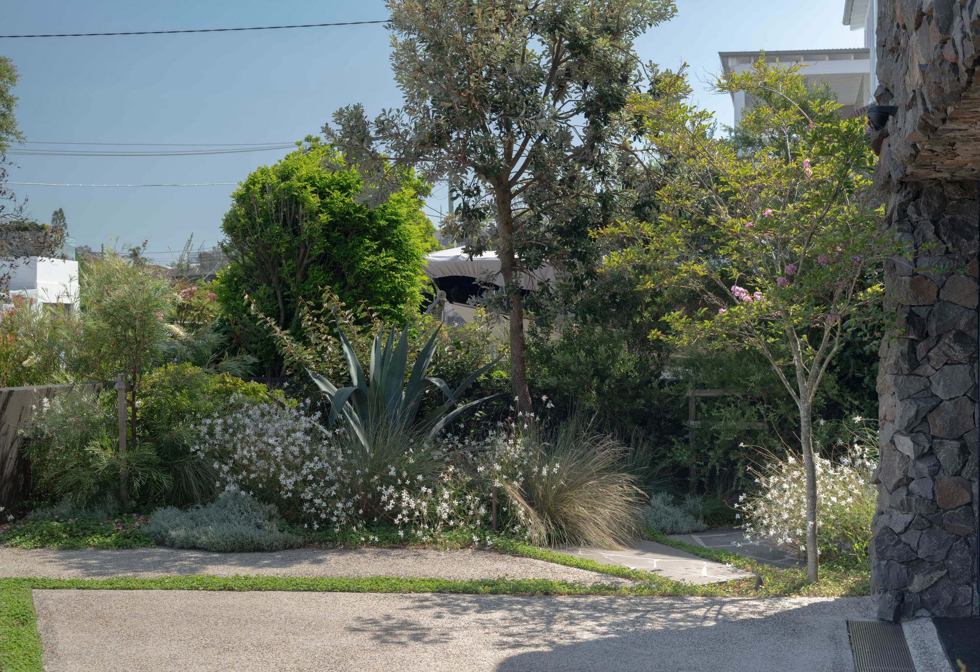 Stone House by Secret Gardens. Front garden with native shrubs, grasses and an agave against the stone façade.
