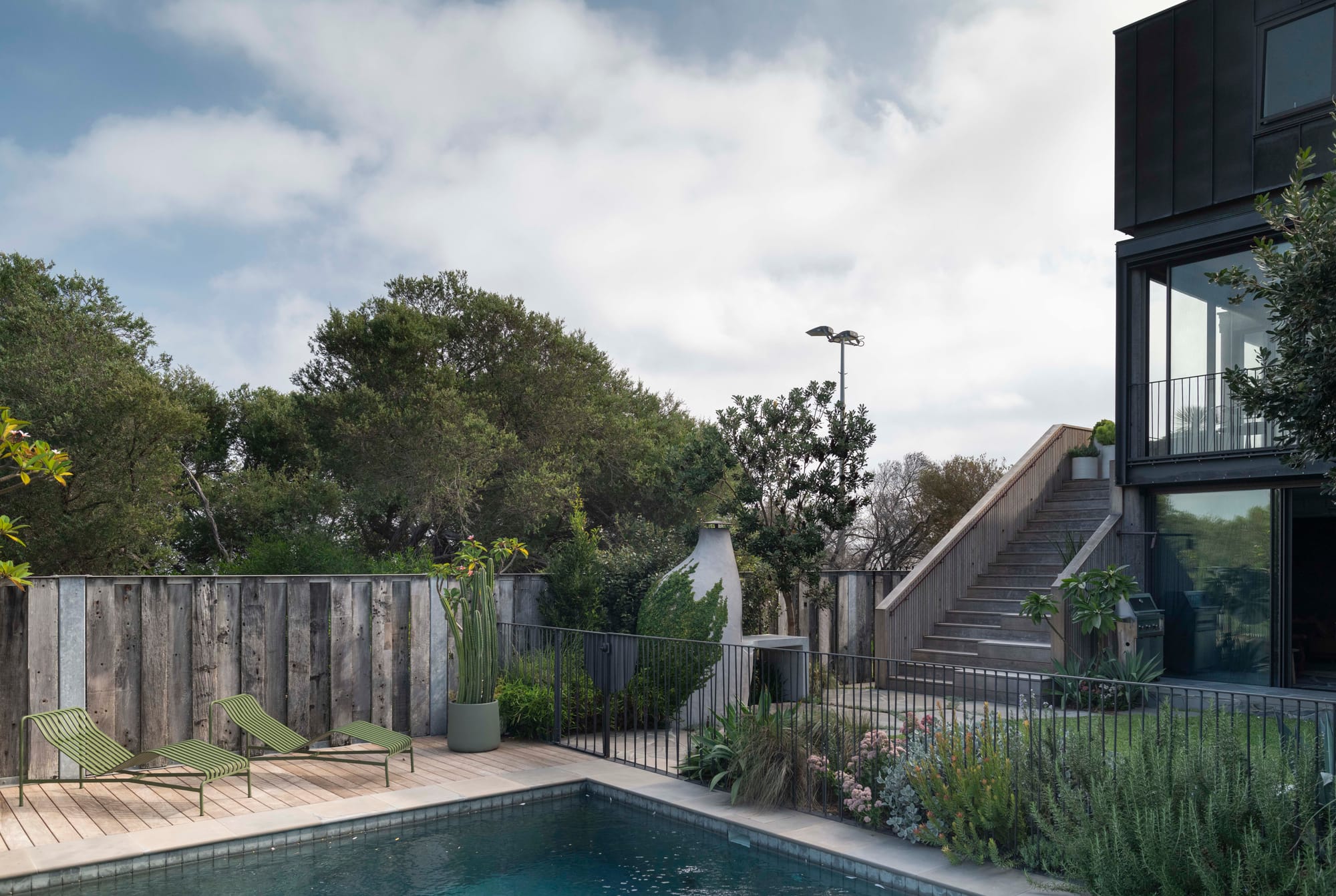 Stone House by Secret Gardens.Pool area at Stone House with timber decking, native planting and sculptural outdoor pizza oven.