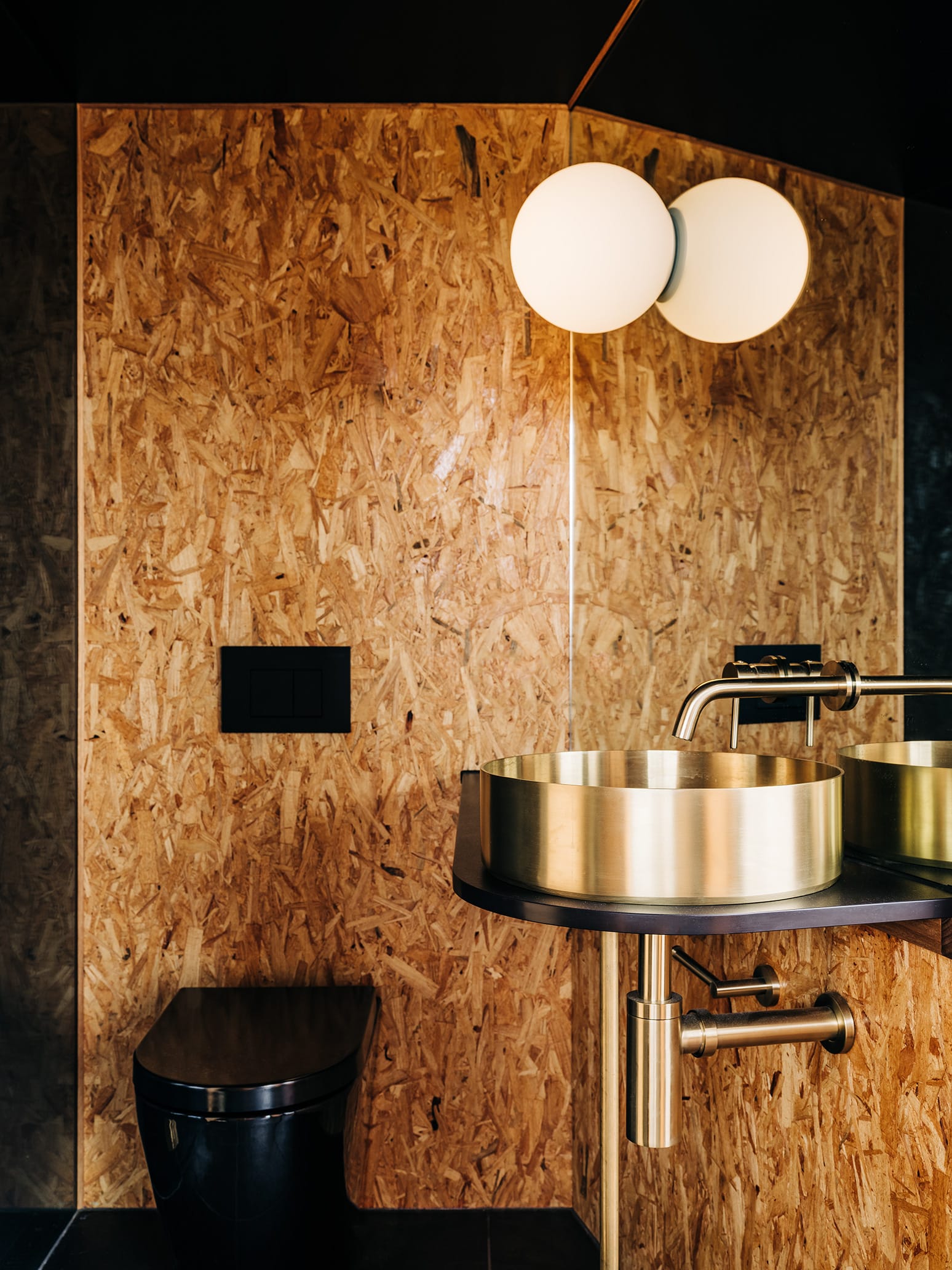 Studio Tasmania. Photography by Adam Gibson. Bathroom with black toilet, gold sink and tapware and wooden walls.