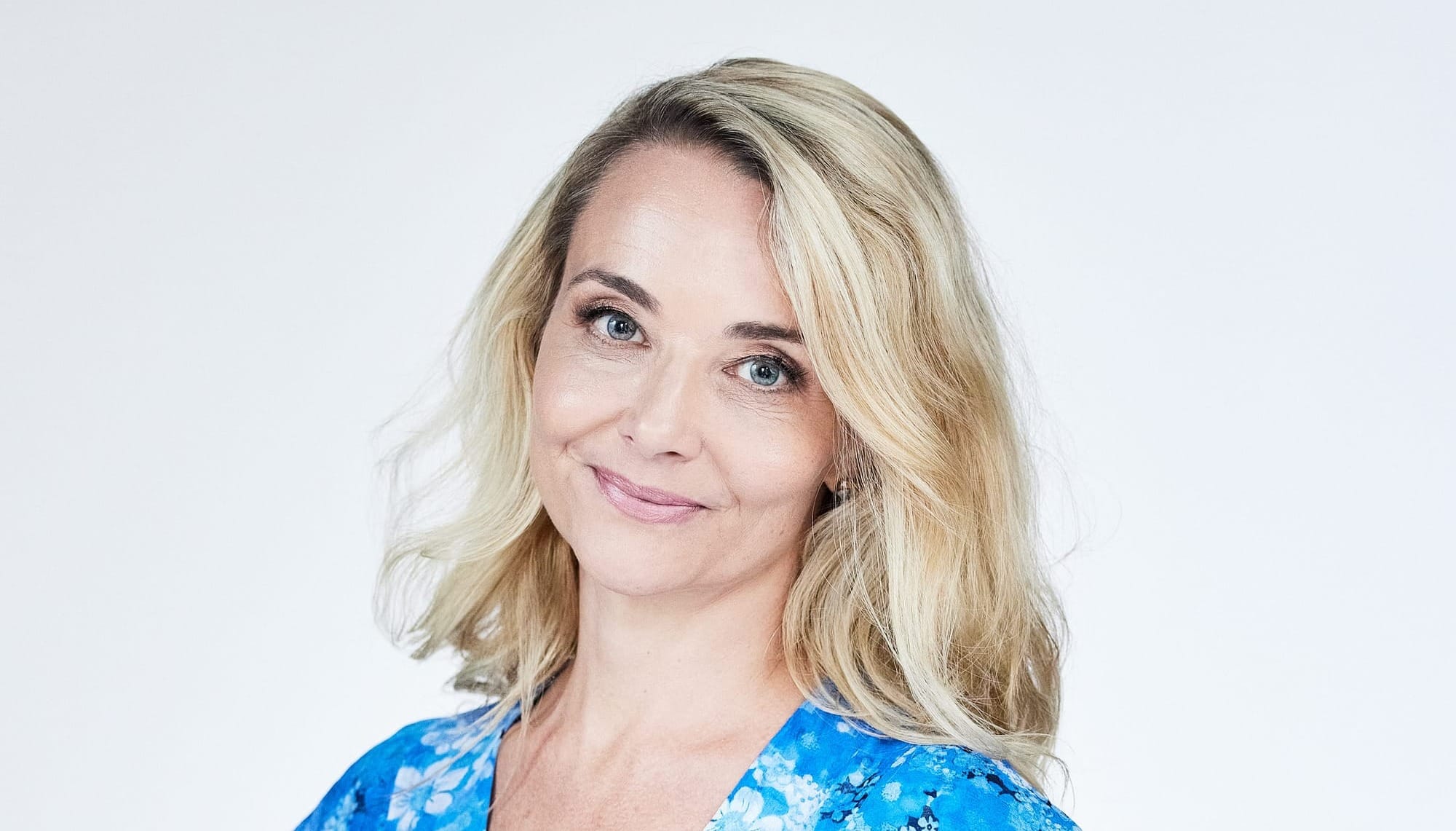 Nathalie Scipioni of Nathalie Scipioni Architects. Blonde woman in blue dresses poses with hands on hips. 