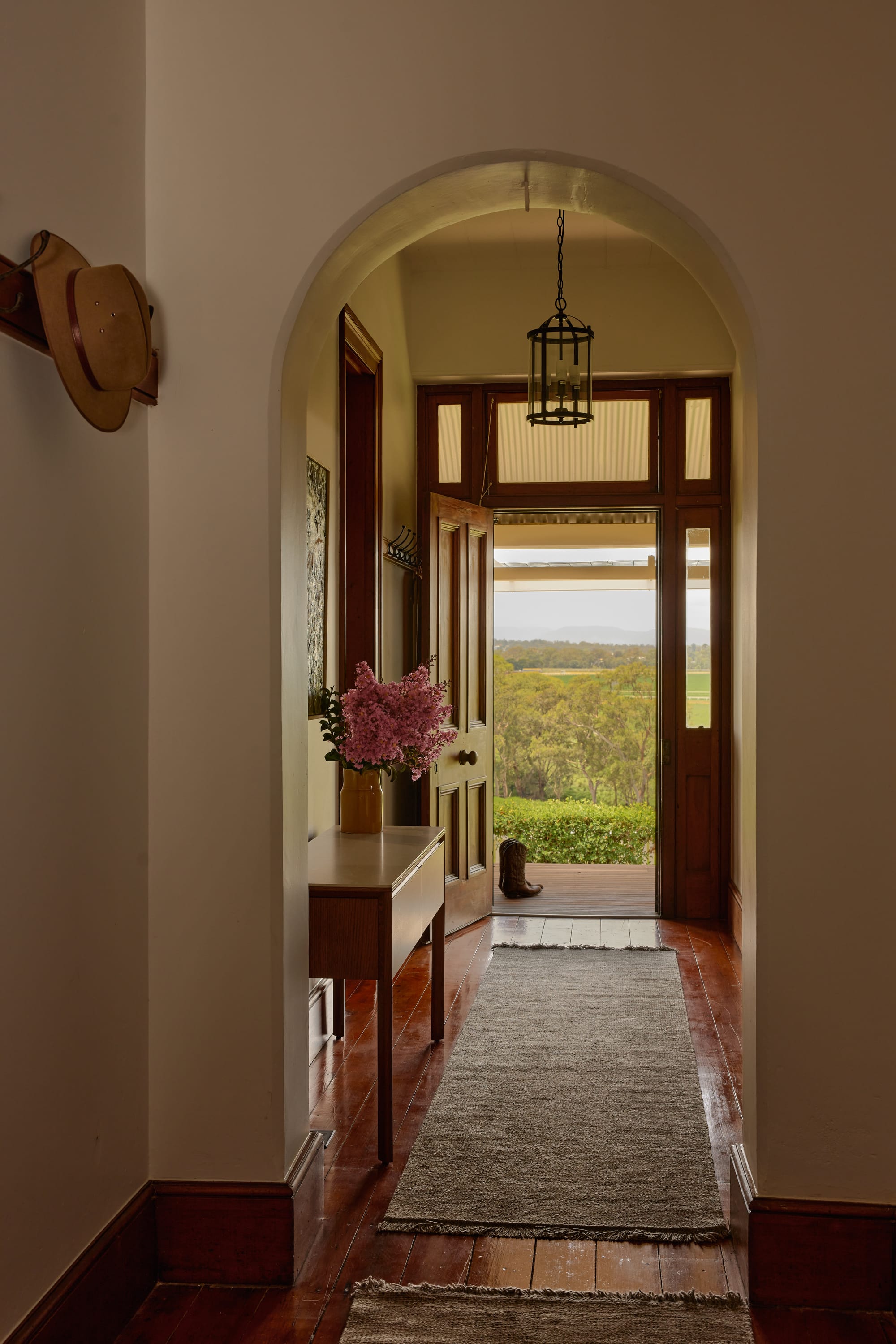 Binnum Homestead by Alexandra Buchanan Architecture. Photography by Cieran Murphy. Hallway with timber floors, archway and double timber door, opening onto timber deck with views over the hills.