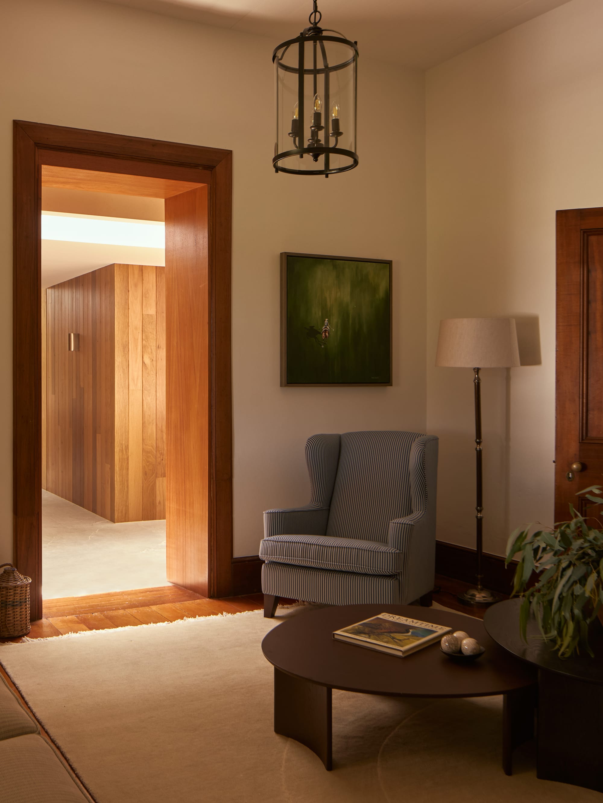 Binnum Homestead by Alexandra Buchanan Architecture. Photography by Cieran Murphy. Sitting room with blue and white striped armchair, black coffee table, timber floors and doorways.