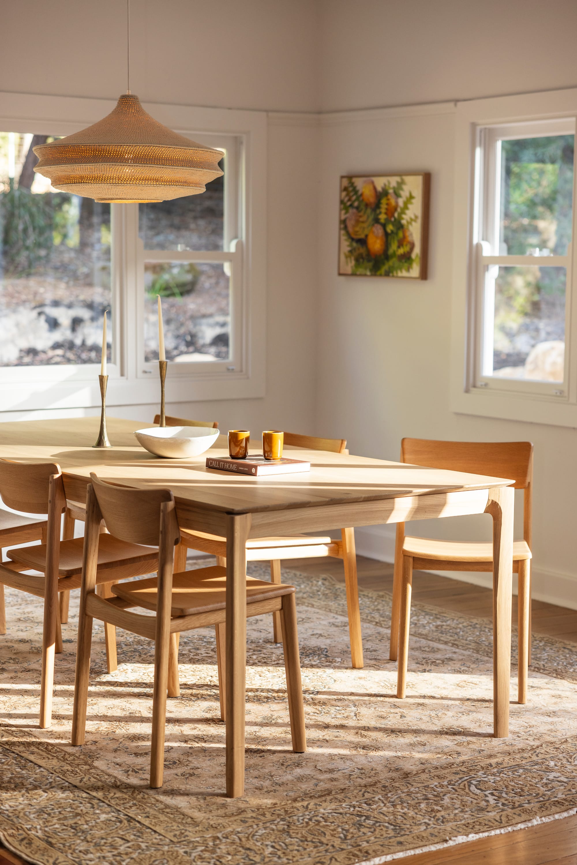 The Cottage by Bel.Bon Design. Photography by Sana Brotherson. Timber dining setting on top of a beige Persian rug, a rattan pendant light and heritage white timber windows frames.