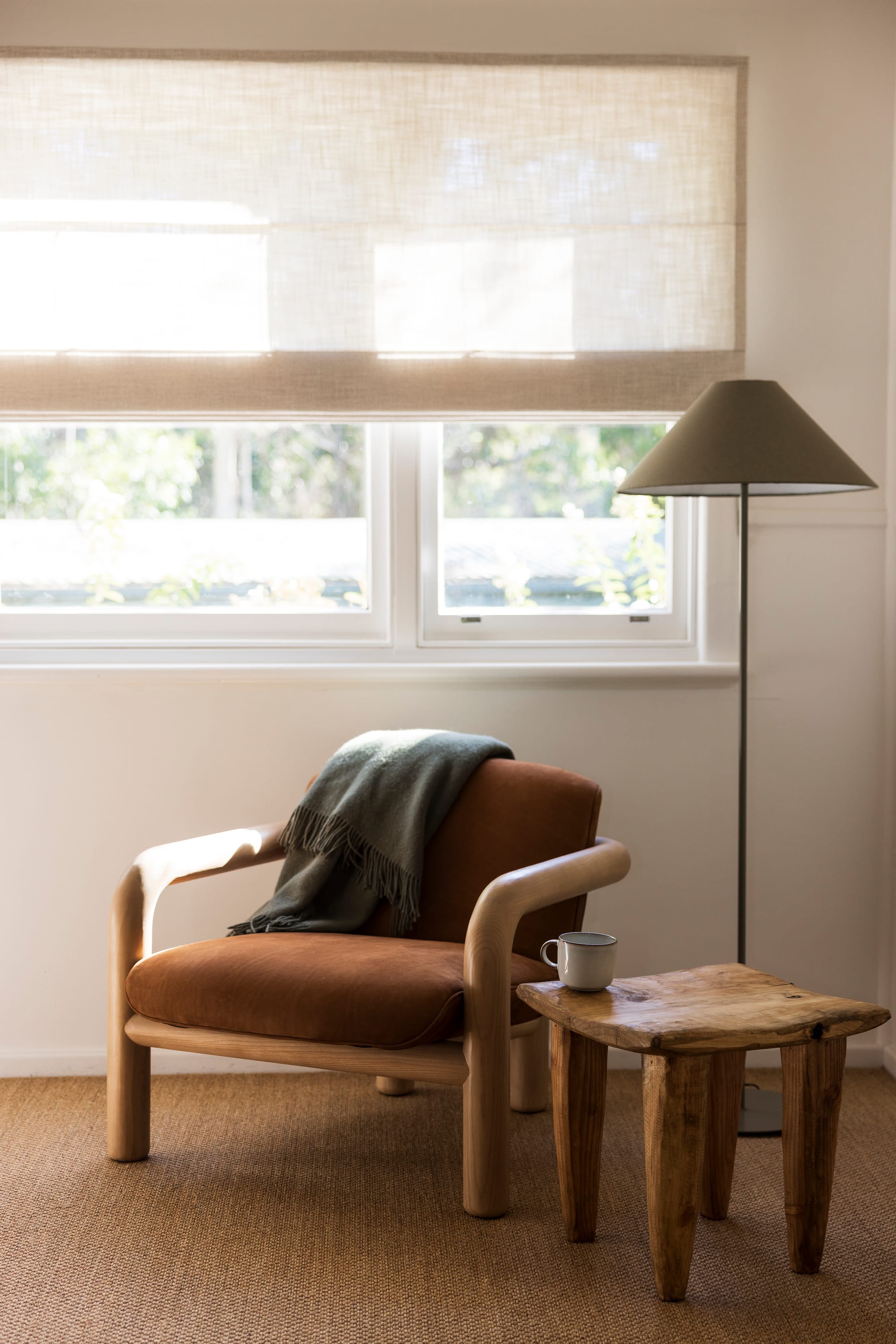 The Cottage by Bel.Bon Design. Photography by Sana Brotherson. Timber armchair with terracotta-coloured upholstery, timber side table, floor lap and jute carpets.