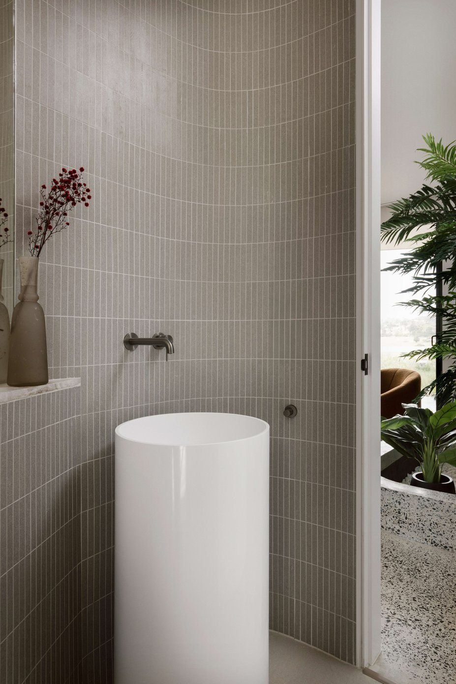 House on the Hill by ENCLAVE Architects. Photography by Elise Scott. Bathroom with round, free standing sink and curved walls tiled with beige fingerling tiles.