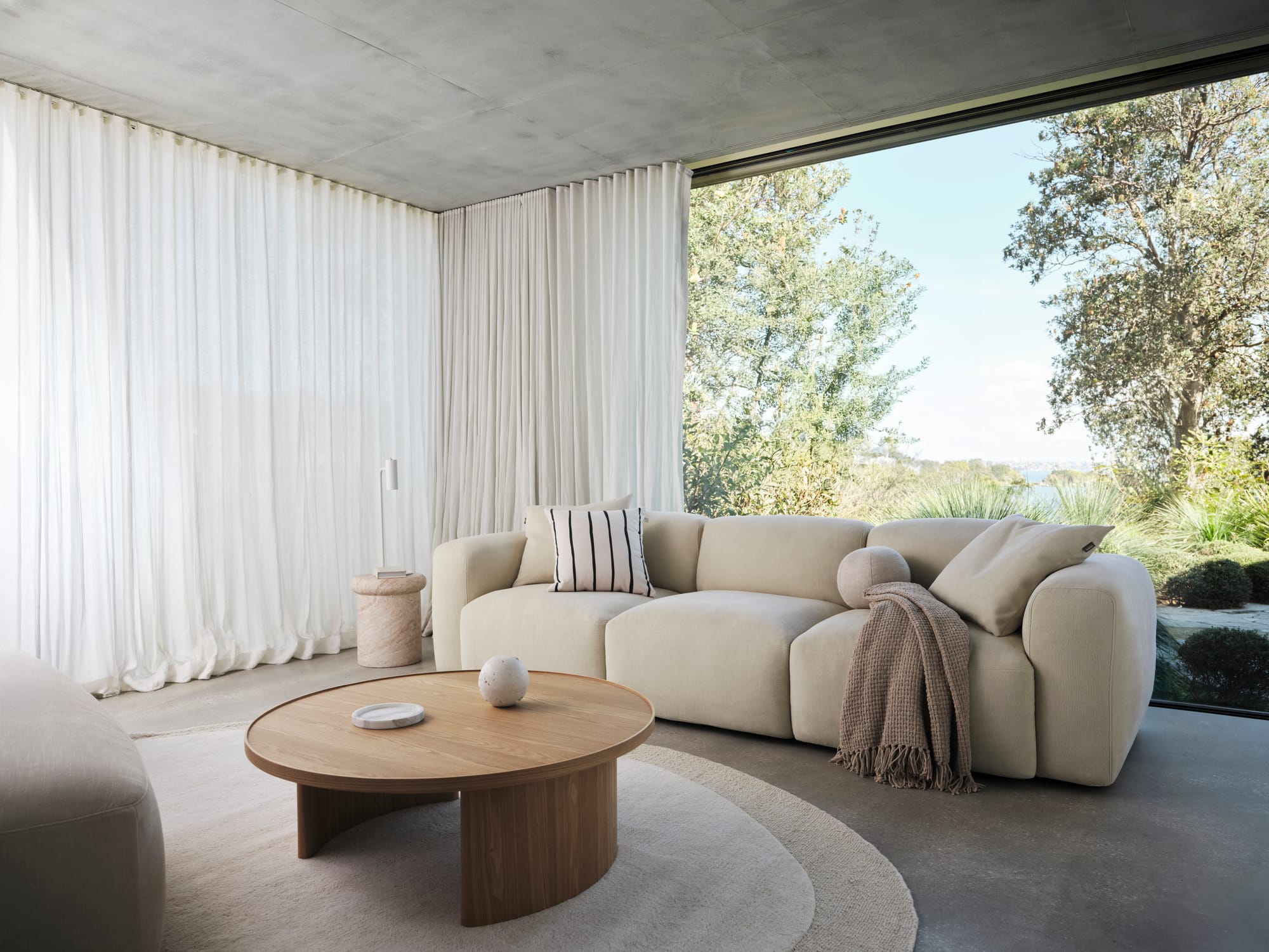 Torquay Sofa in Pearl Moon by Koala. White modular sofa in room with concrete floors and full length white sheers.