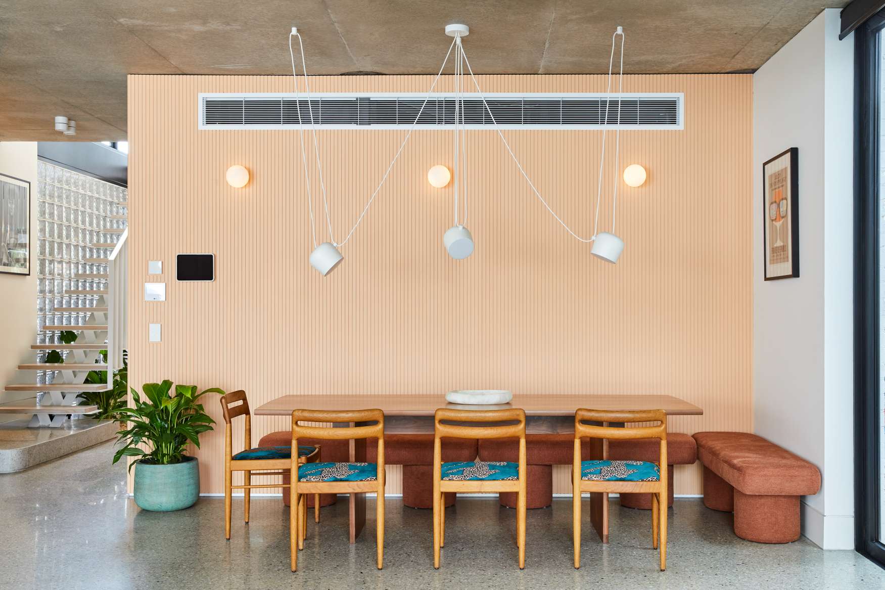 Park St by SGKS ARCH. Photography by Tania Lee. Dining space with peach wall, timber dining set, and handing white lights.