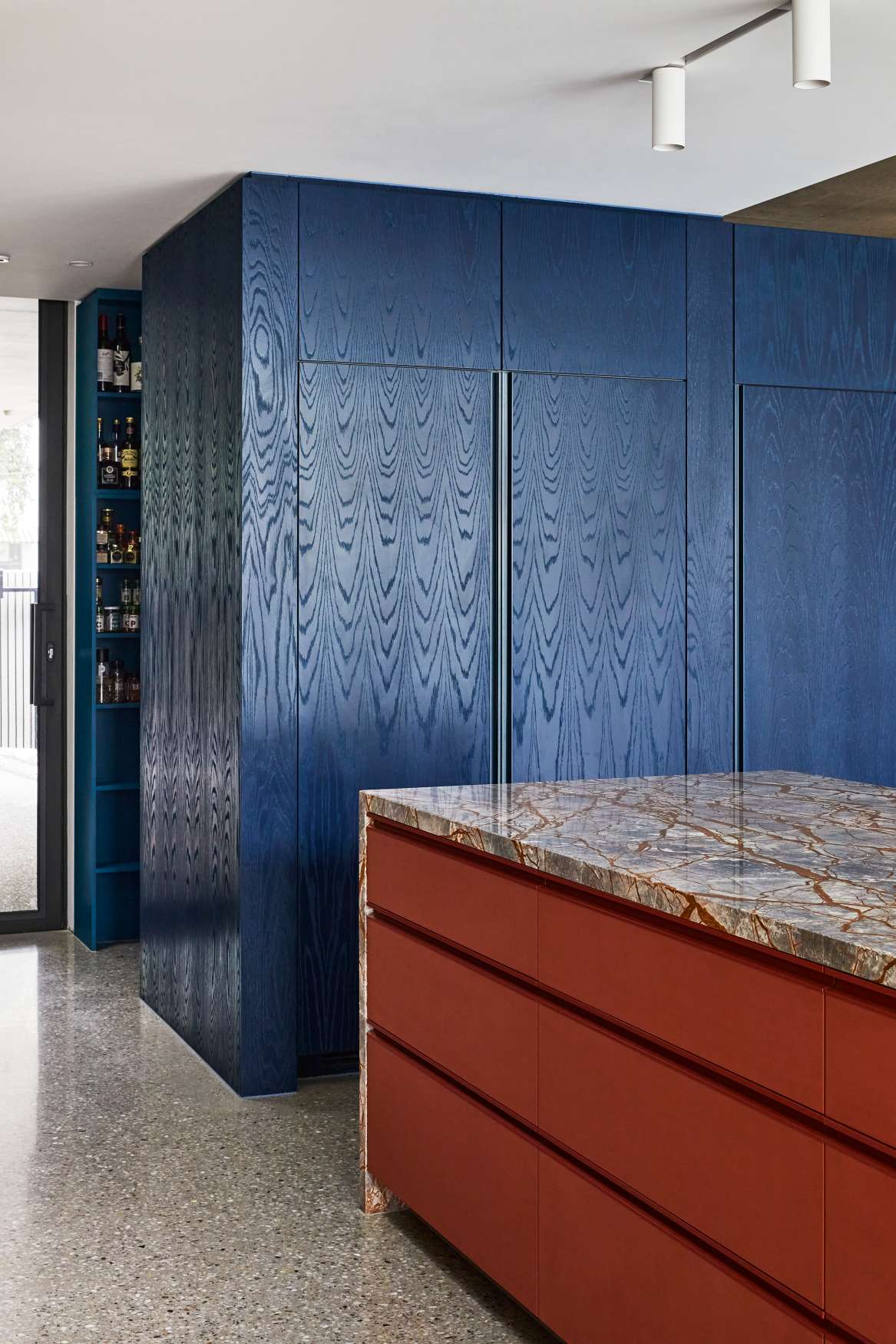 Park St by SGKS ARCH. Photography by Tania Lee. Kitchen counter with terracotta drawer faces, veined stone countertop and navy timber cabinetry.