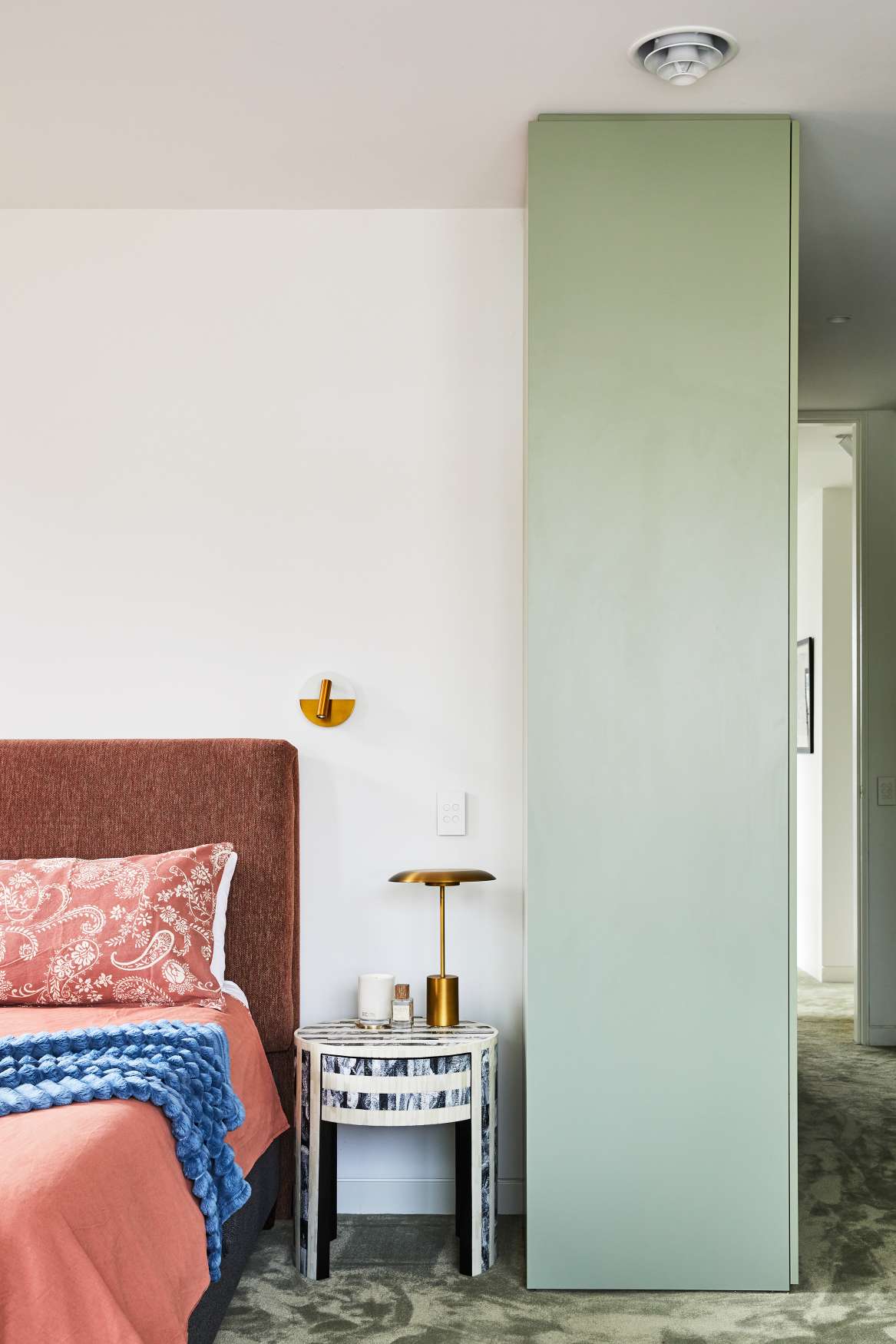 Park St by SGKS ARCH. Photography by Tania Lee. Bedroom with sage carpets, mint and white walls, burnt orange bedhead and bedding and a navy bedside table.