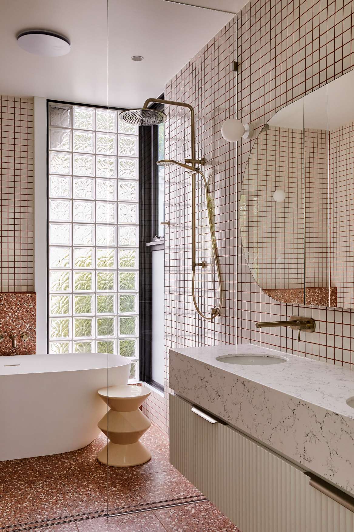 Park St by SGKS ARCH. Photography by Tania Lee. Bathroom with burnt orange tiled floors, white bathtub, white stone countertop and white tiled walls with red grout.
