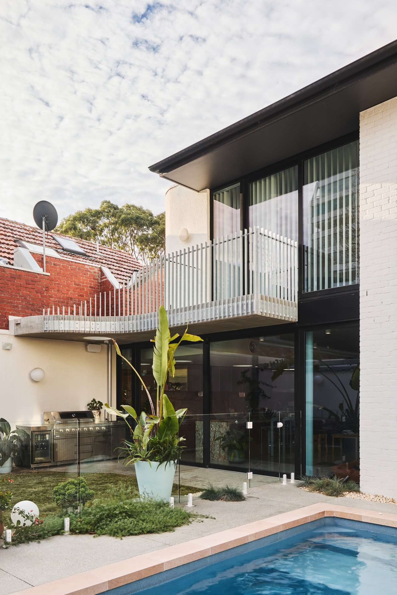 Park St by SGKS ARCH. Photography by Tania Lee. Backyard with a pool, grassed area, paved patio with barbeque and balcony.