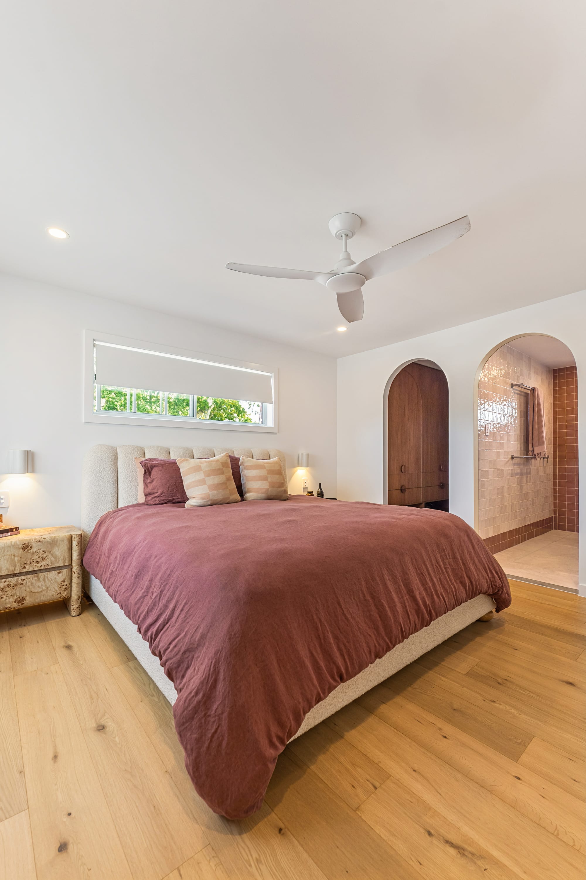 Chardonnay Court House by Studio MDM. Photography by Focl Media. Bedroom with timber floors, arched doors leading to walk in wardrobe and ensuite, and plum linen bedding. 